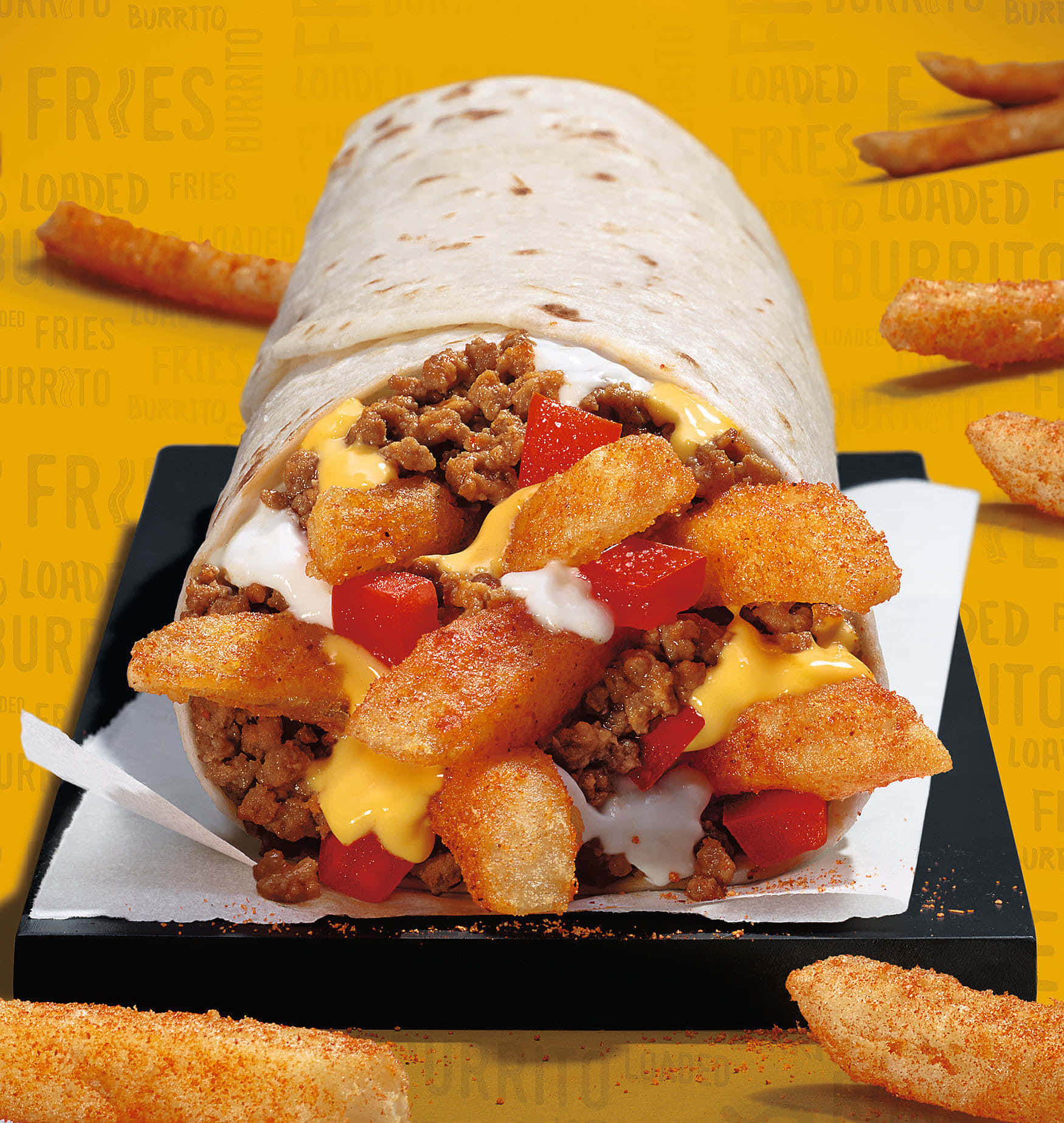 Taco Bell 桌布 壁紙 — 一個滿載的墨西哥捲餅，塞滿了酥脆的薯條、起司醬和牛絞肉，放在黑色盤子上，襯以鮮黃色背景。