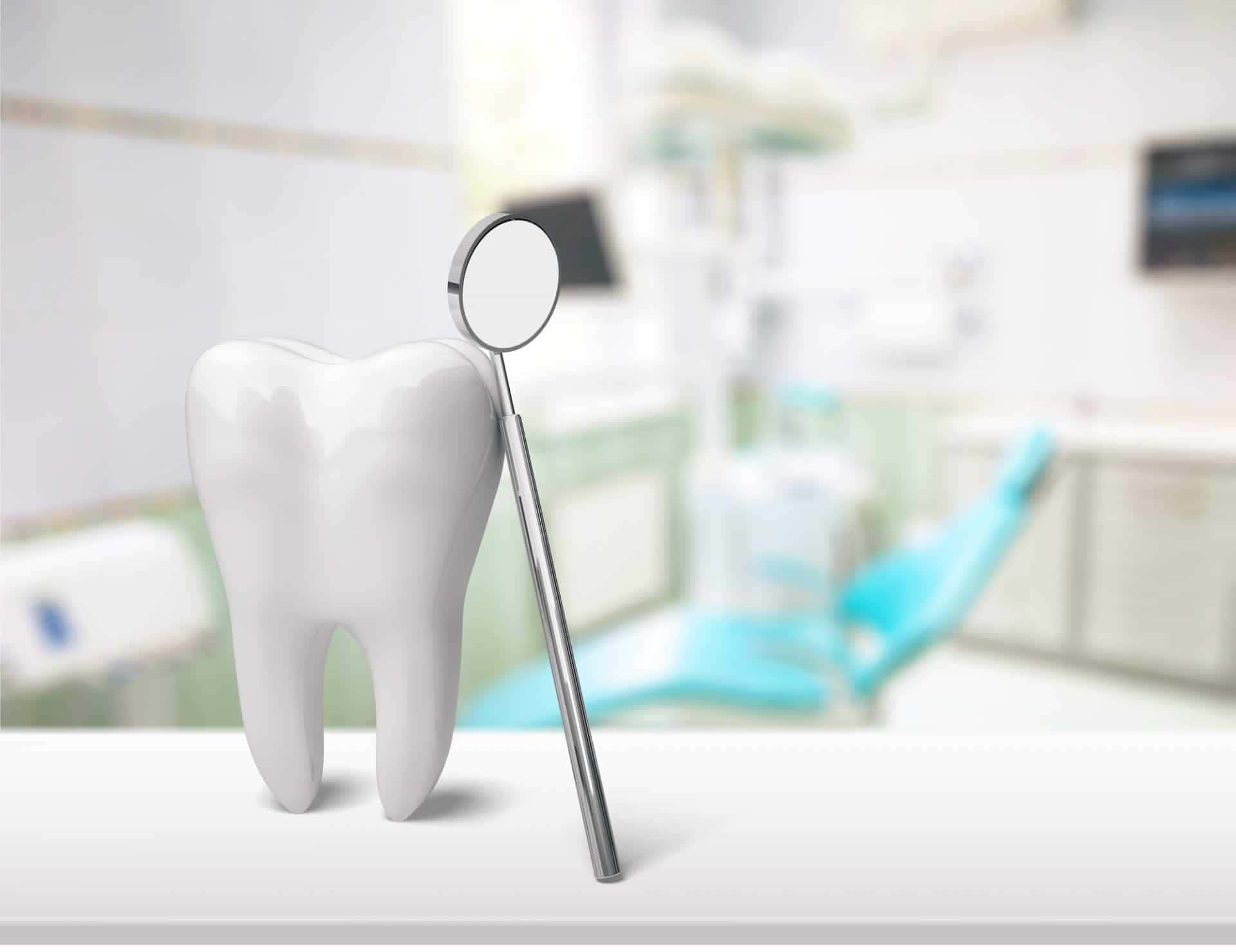 Tooth 桌布 壁紙 — 一個潔白的牙齒模型放在牙科診所乾淨的櫃檯上，旁邊有一個牙科鏡，背景輕微模糊。