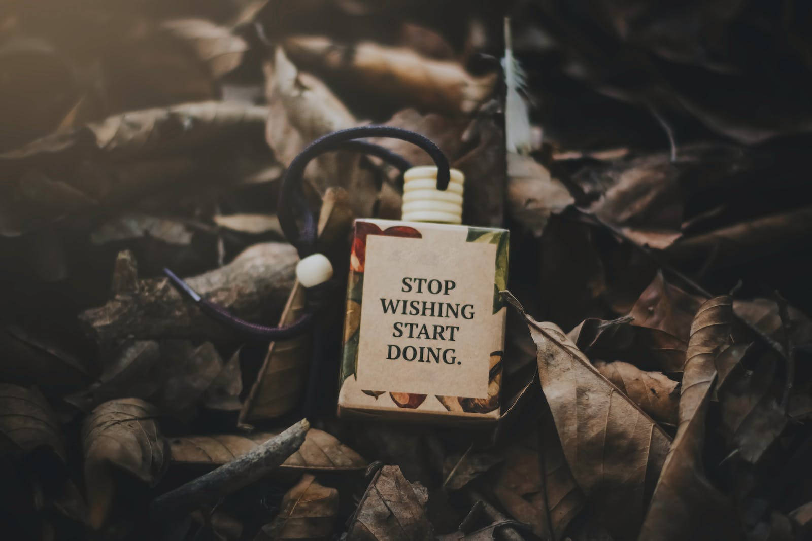 Motivational Quotes 桌布 壁紙 — 一個激勵語句瓶藏在乾燥的秋葉中，沐浴在柔和自然光下。