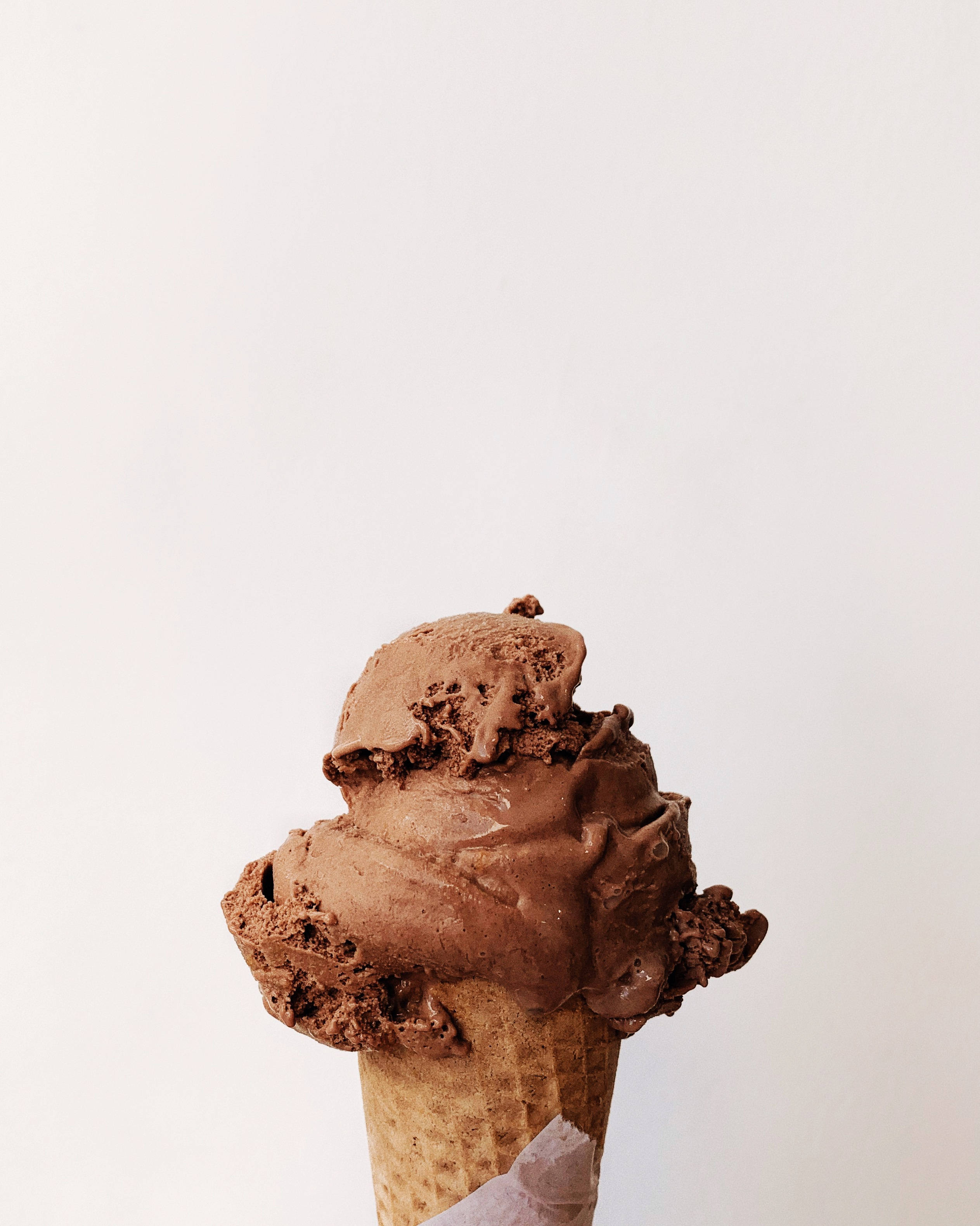 Ice Cream 桌布 壁紙 — 一個濃郁的巧克力冰淇淋甜筒，帶有紋理漩渦，放在潔淨的白色背景上。