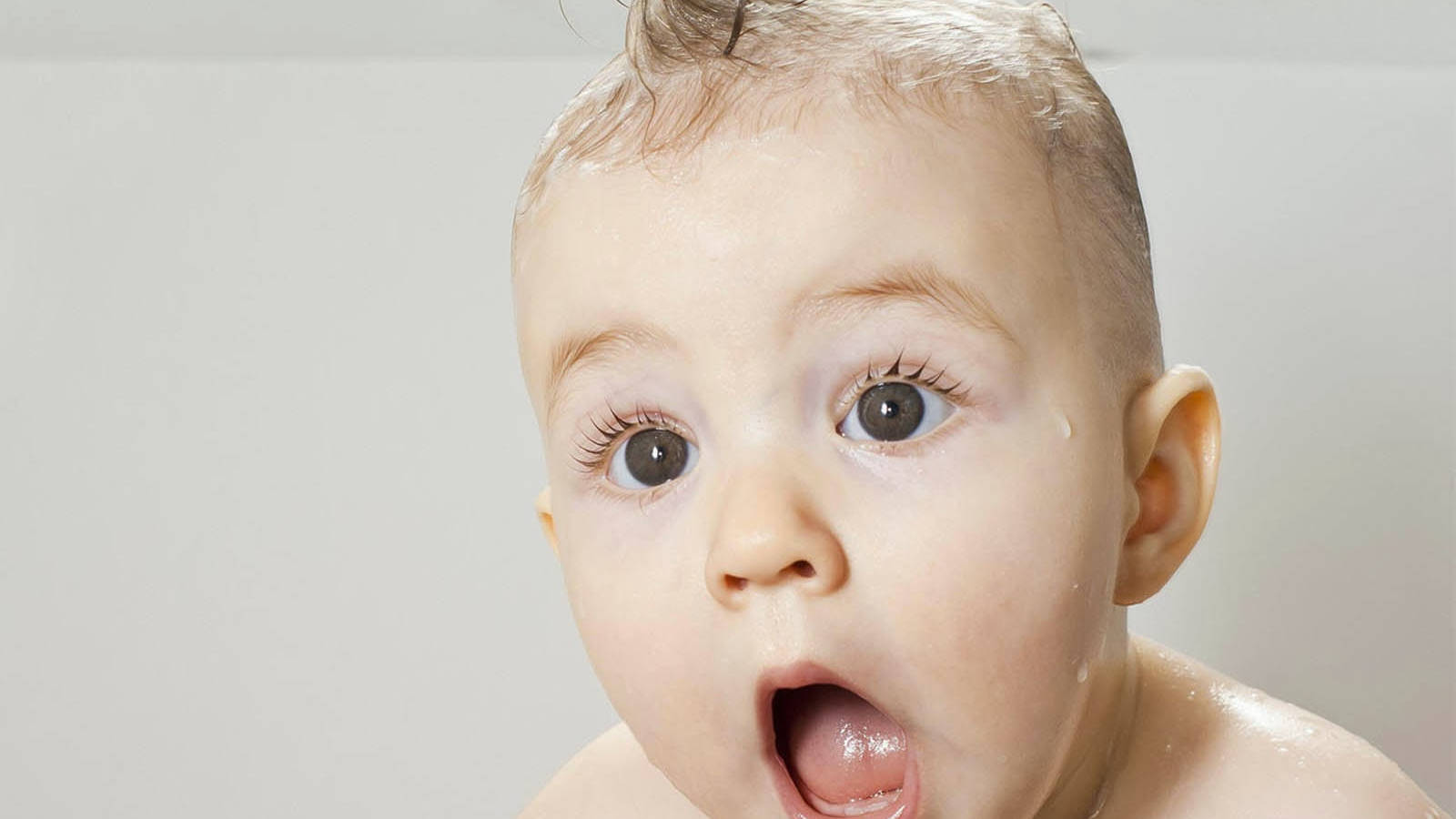Funny Baby 桌布 壁紙 — 一個濕漉漉的嬰兒特寫，睜大眼睛、張開嘴巴，在淋浴中露出驚訝的表情。