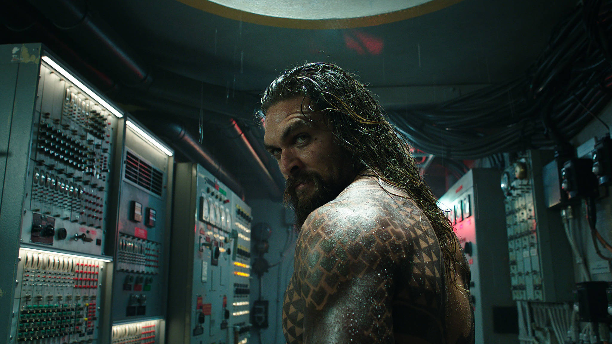 Aquaman 桌布 壁紙 — 一個濕透的鬍鬚男，身上有部落紋身，在昏暗的控制室裡，周圍是發光的面板和滴水的管道，他凝視著。