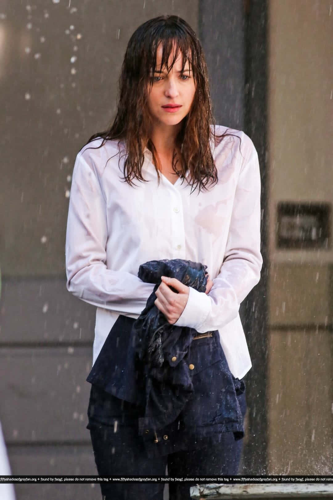 電影動圖 桌布 壁紙 — 一個濕髮的女人站在落雨中，將一件濕透的夾克抱在胸前。