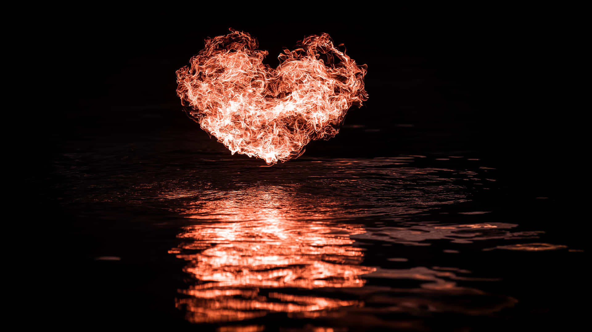 A burning heart floating above water 壁紙 — 一個火熱的心形懸浮在黑暗的水面上，在漣漪的表面投射出熾熱的橙色倒影。