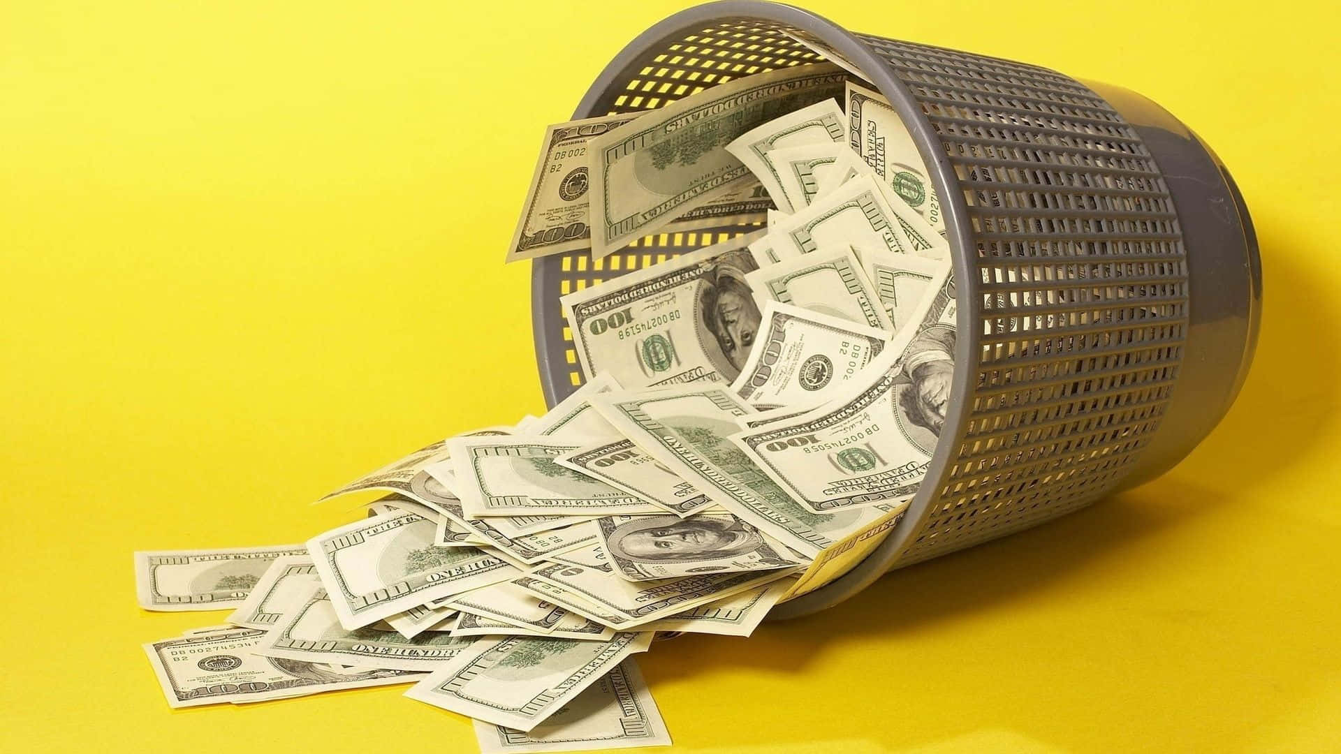 Falling Money 桌布 壁紙 — 一個灰色有孔垃圾桶翻倒，數百張美元鈔票散落在明亮的黃色背景上。