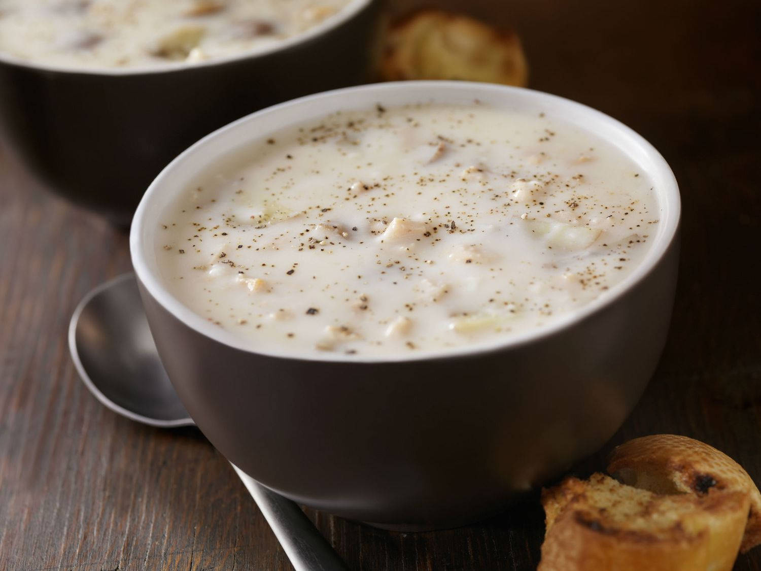 Soup 桌布 壁紙 — 一個灰色碗中的奶油白色周打湯，飾以黑胡椒，並在木桌上與烤麵包一起享用。