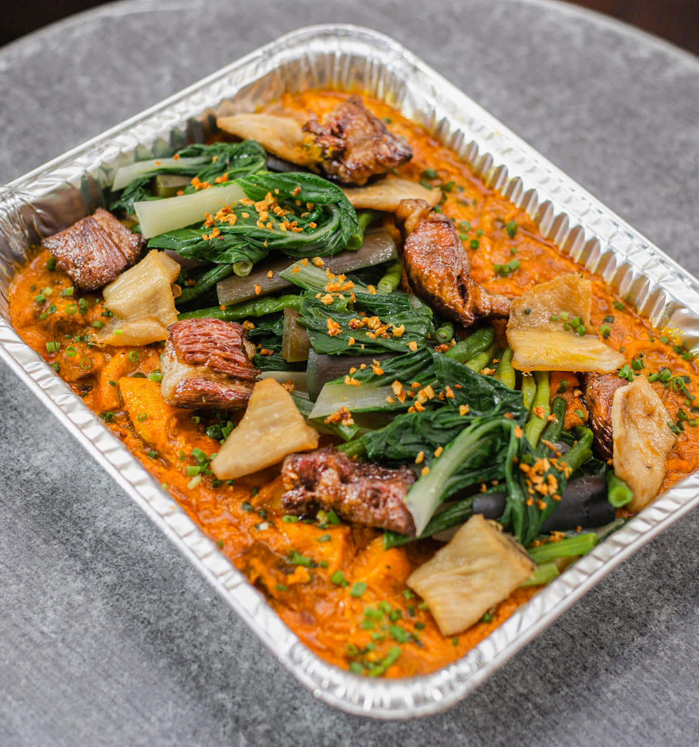 meat 桌布 壁紙 — 一個灰色表面上的鋁箔盤裡有充滿活力的橙色燉菜，配有青菜、肉和豆腐。