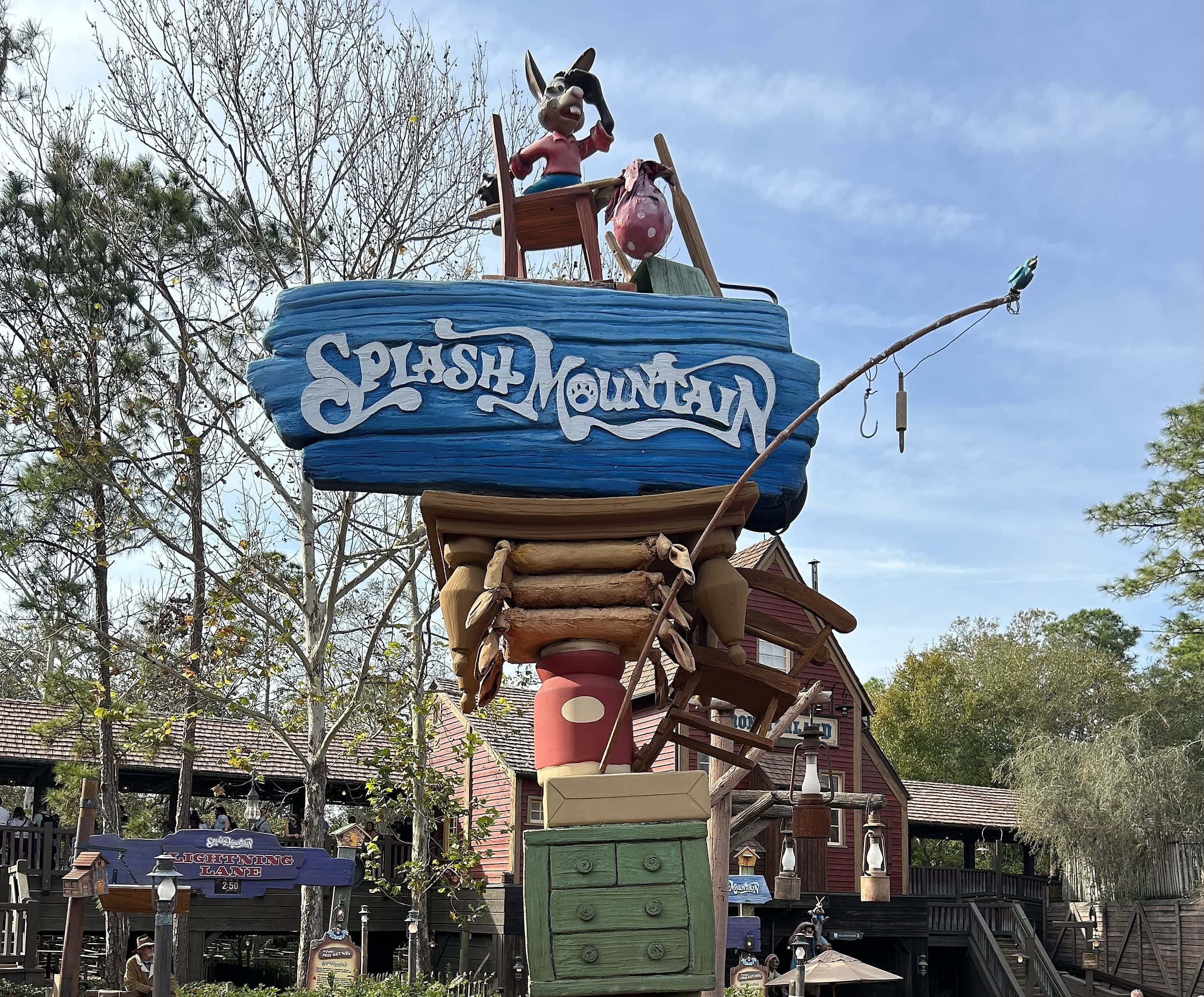 Splash Mountain 桌布 壁紙 — 一個為Splash Mountain而設的奇特木牌，上面有一隻卡通驢子在藍色木頭上揮手，釣竿伸向晴朗的天空。