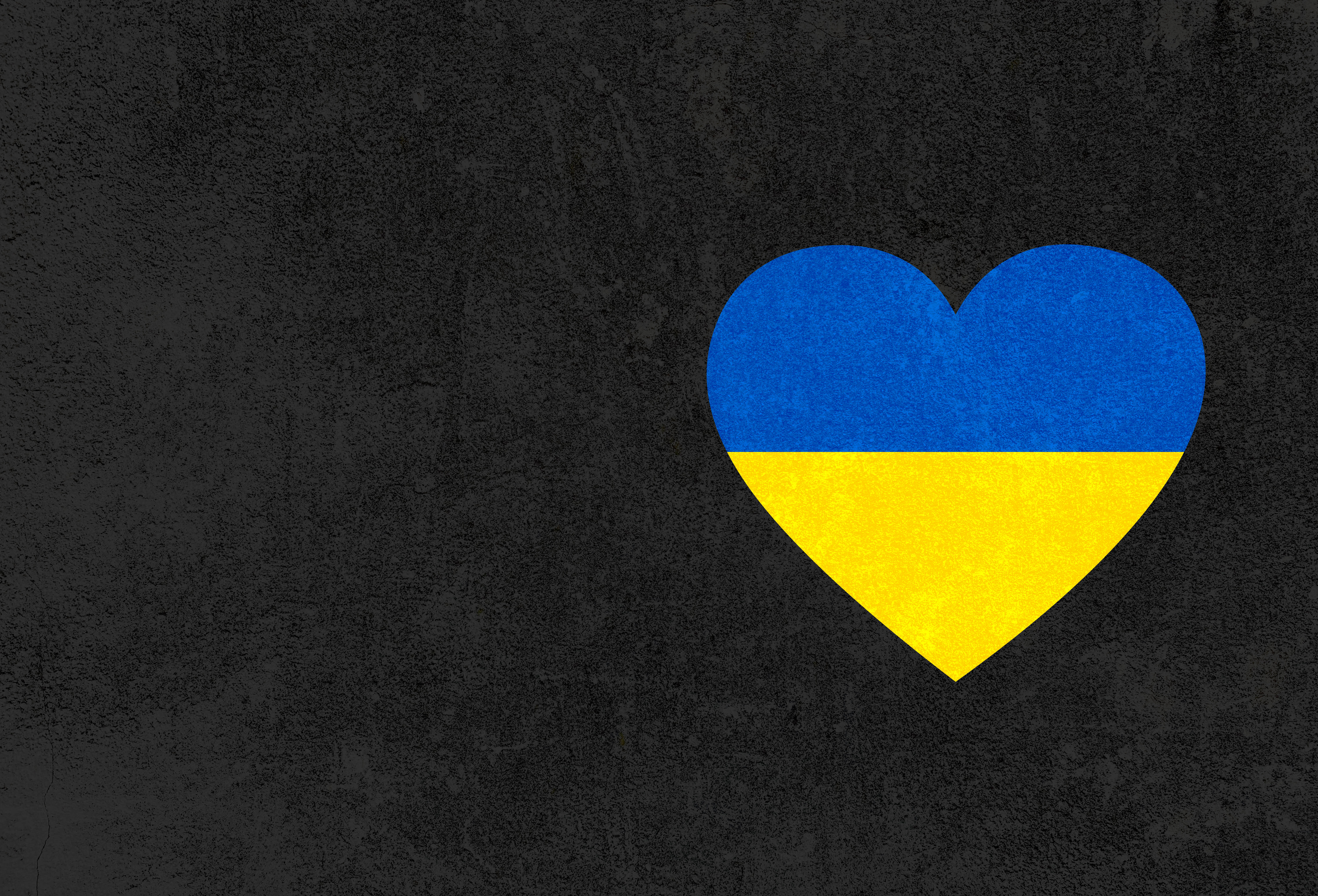 Ukraine 桌布 壁紙 — 一個烏克蘭國旗形狀的心臟，大膽地矗立在粗糙的深灰色混凝土牆上。