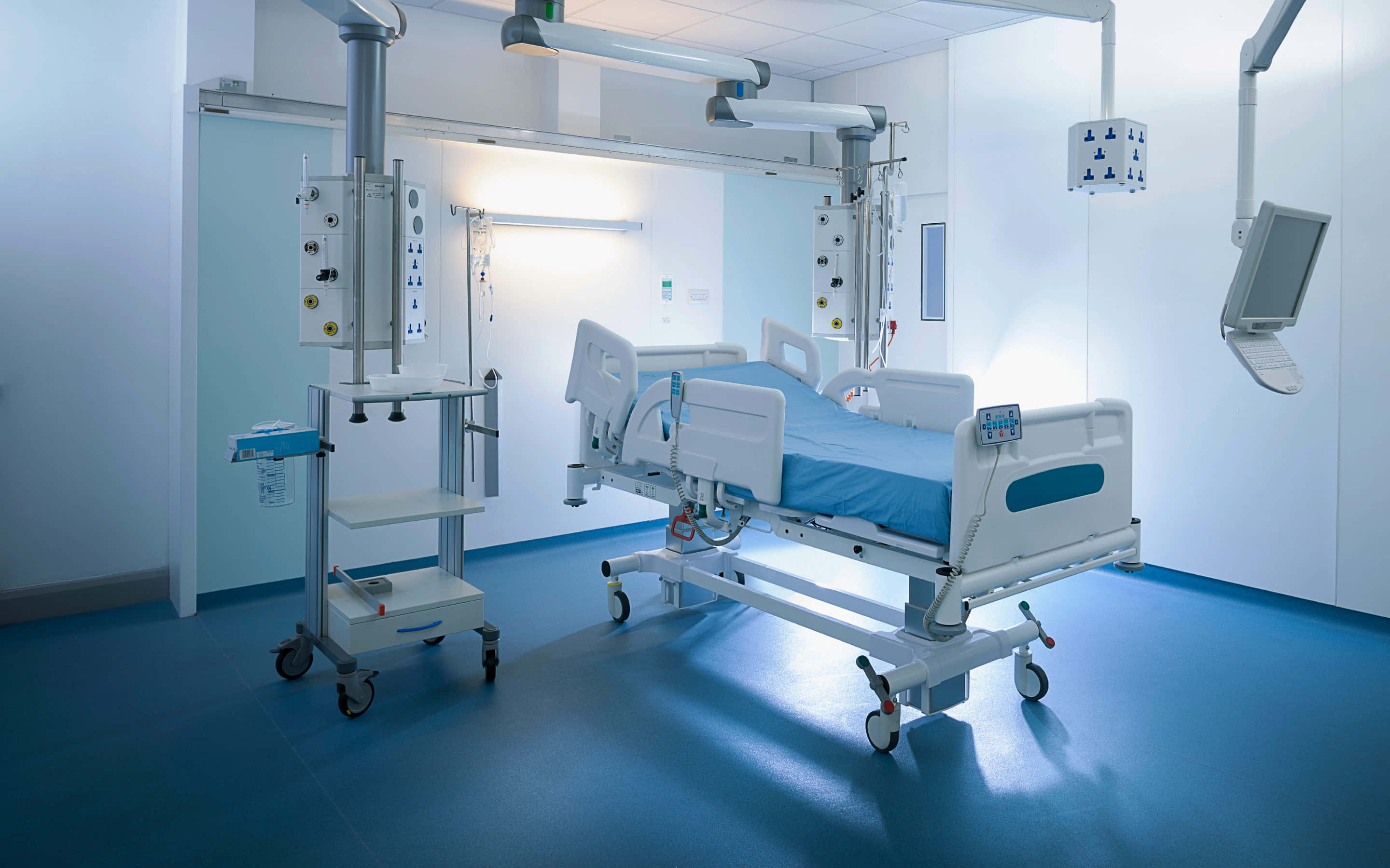 Hospital Bed 桌布 壁紙 — 一個無菌的醫院房間，內有醫療床、輸液架和顯示器，在明亮的螢光燈下。