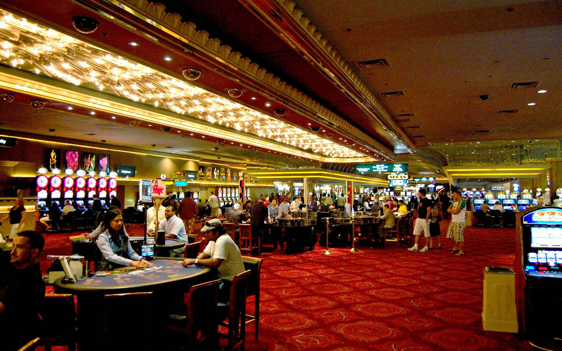 Poker 桌布 壁紙 — 一個熙熙攘攘的賭場內部，玩家在華麗金色燈光和紅色地毯下的廿一點牌桌上。