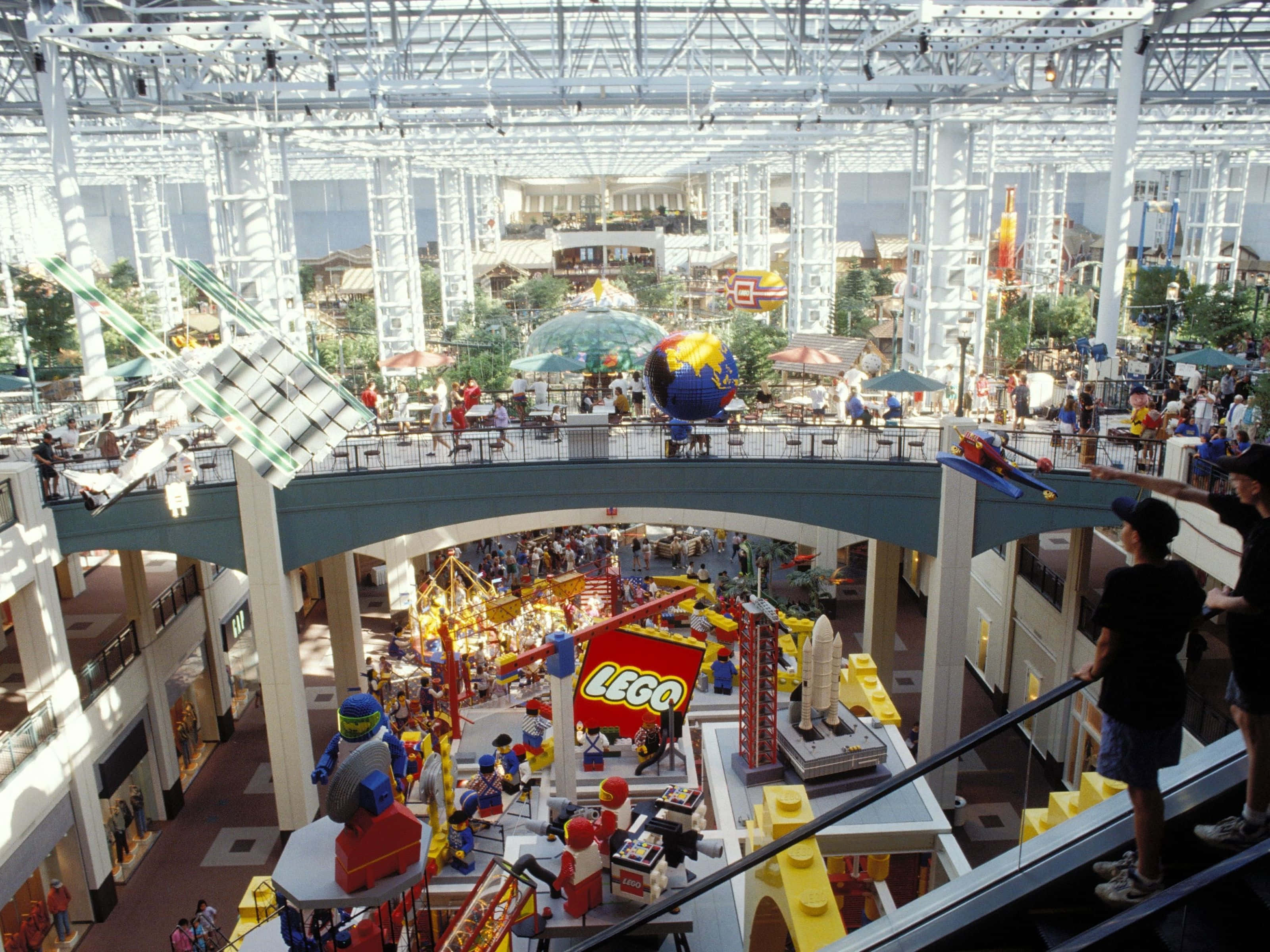Mall Of America 桌布 壁紙 — 一個熱鬧的室內LEGO主題景點，設有巨大的彩色積木結構，遊客在玻璃屋頂下探索多層遊樂區。