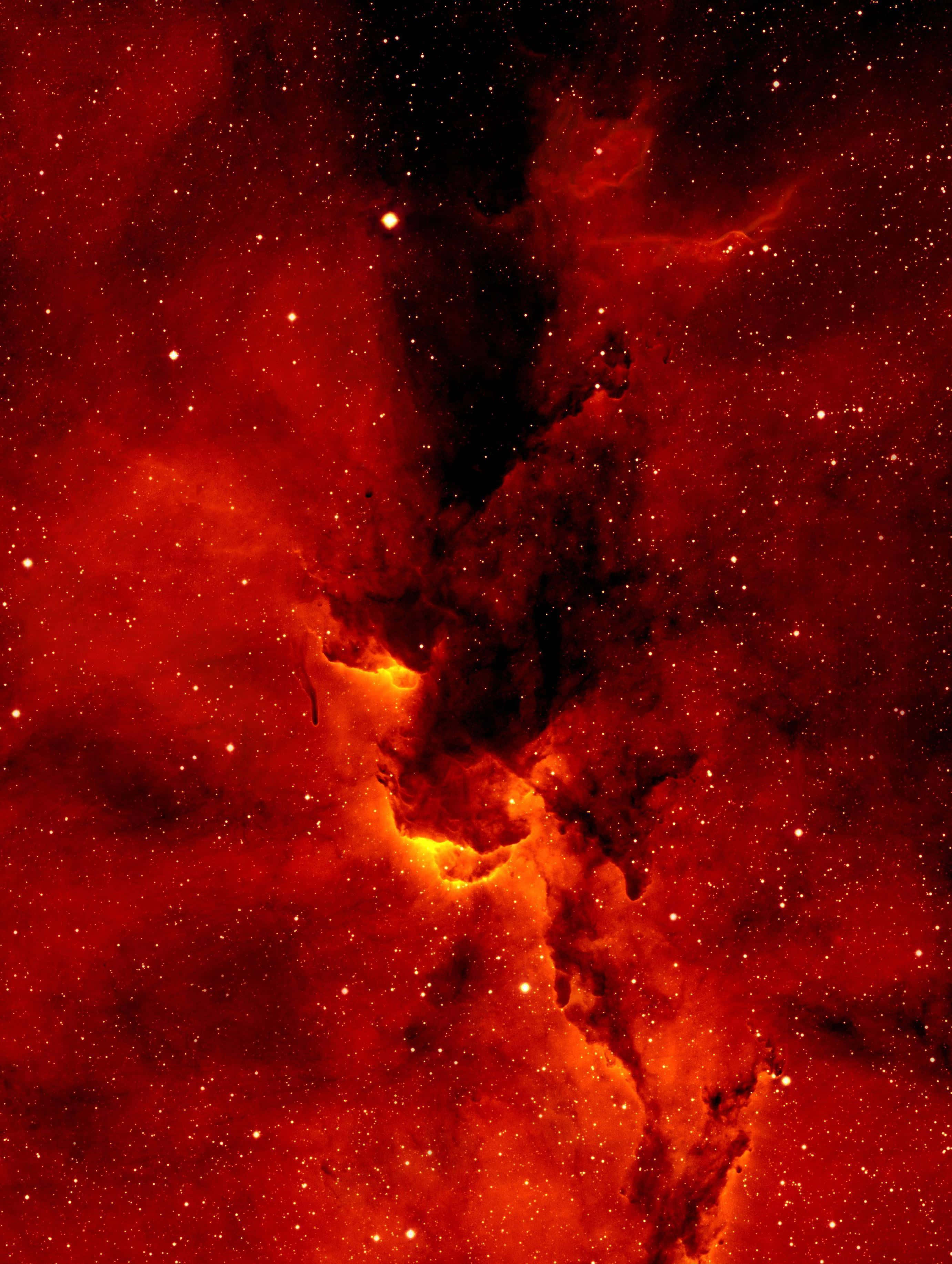 霓虹紅 桌布 壁紙 — 一個熾熱的紅色星雲，帶有發光的橙色核心和黑暗的宇宙塵埃，在星場中旋轉。