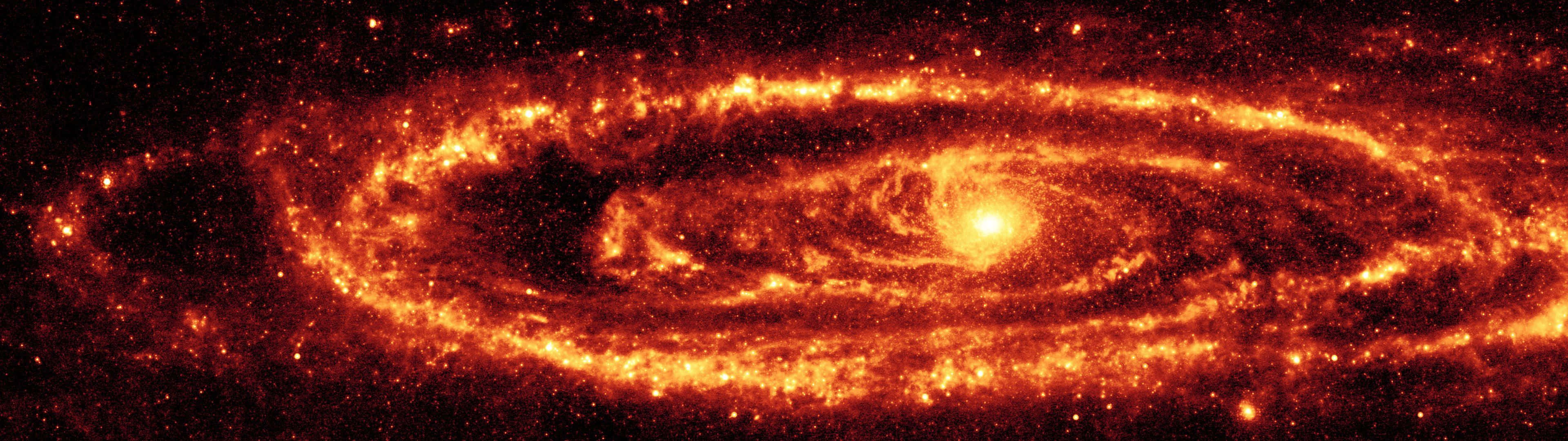 桌布 壁紙 — 一個熾熱的螺旋星系在佈滿星光的黑色虛空中散發出強烈的橙色和紅色色調。