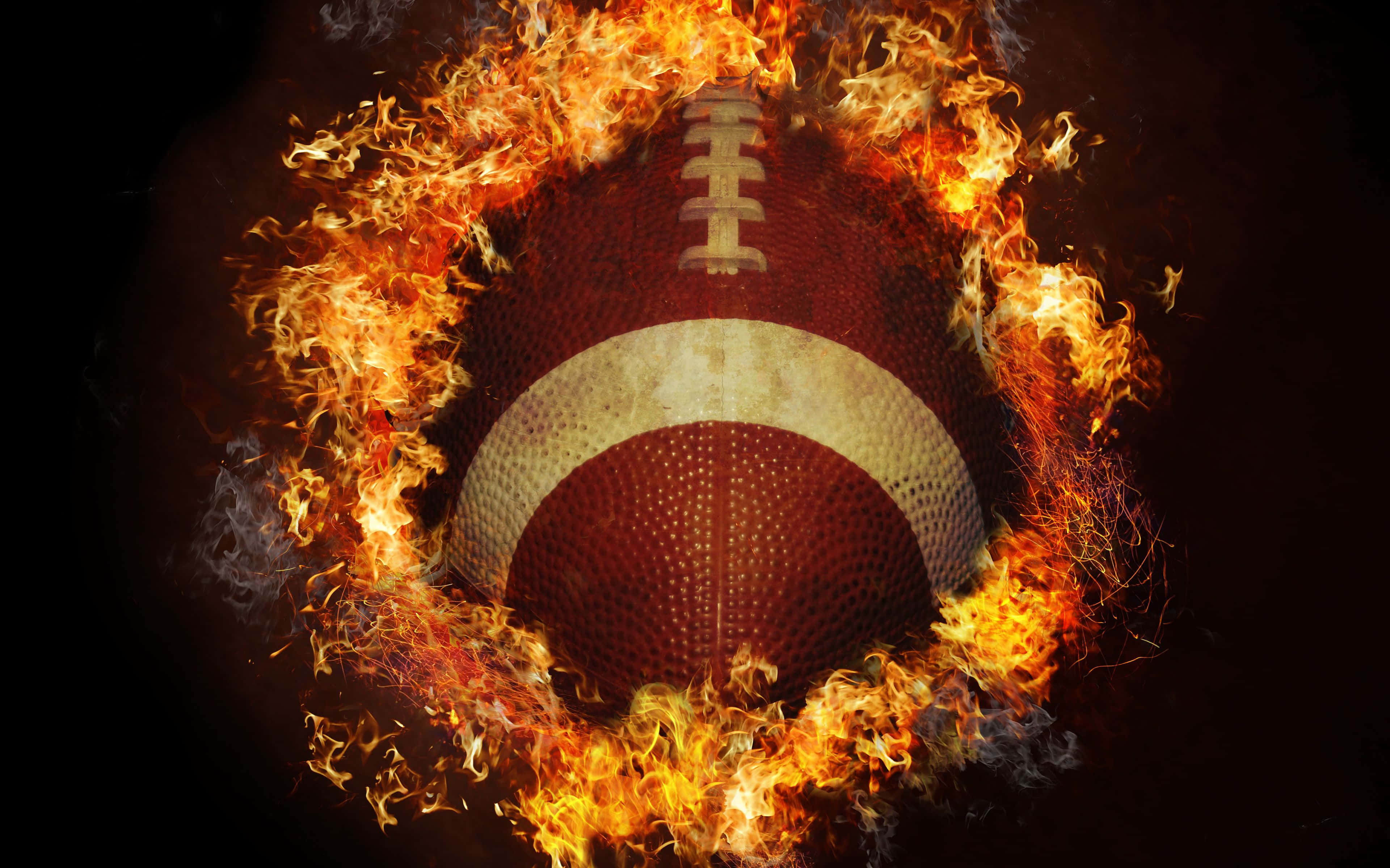 Football On Fire 桌布 壁紙 — 一個燃燒的美式足球，被猛烈的橙色火焰吞噬，背景為深色。