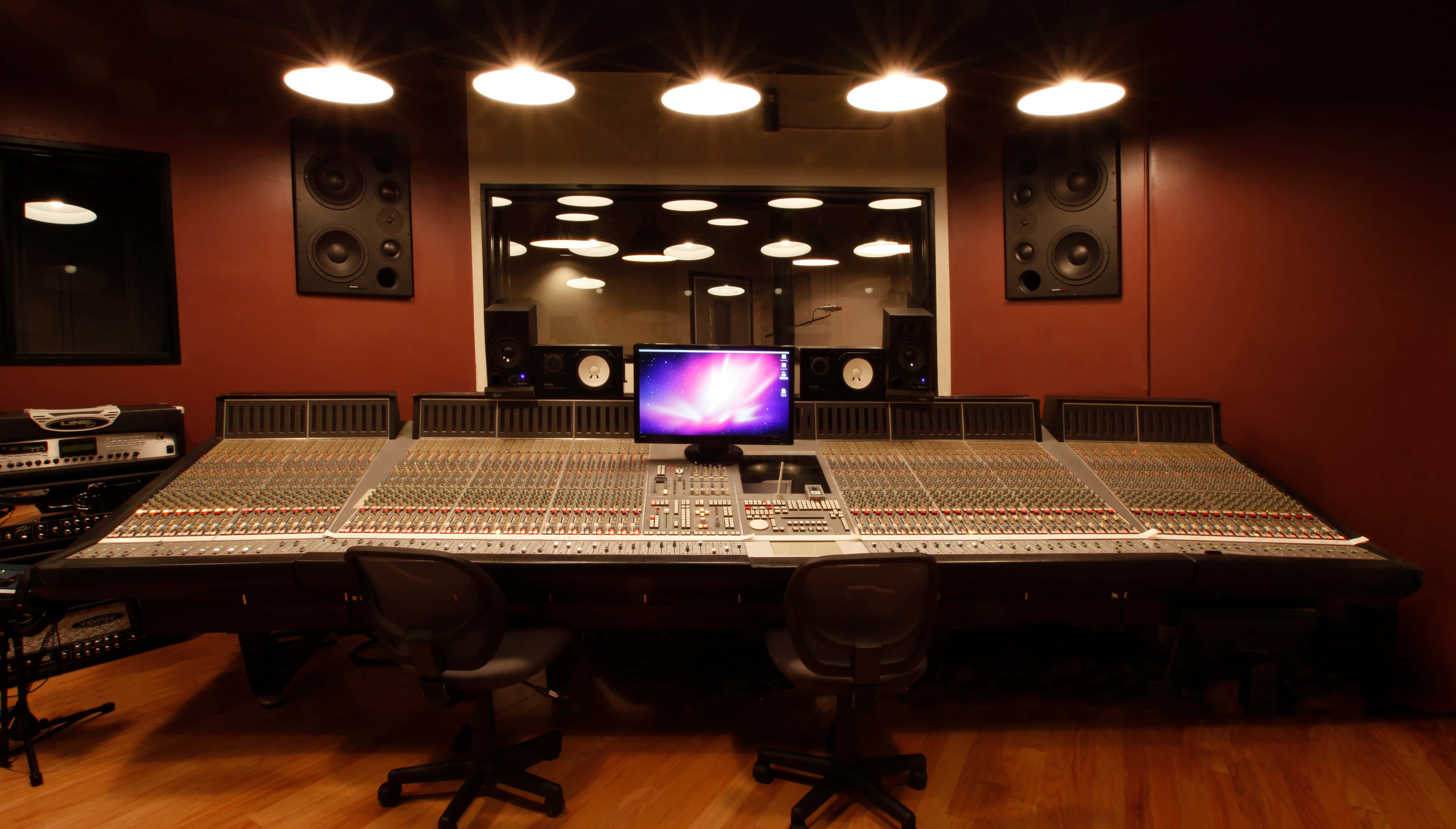 Studio 桌布 壁紙 — 一個燈光昏暗的專業錄音室，大型混音台在溫暖的天花板燈光下閃耀。