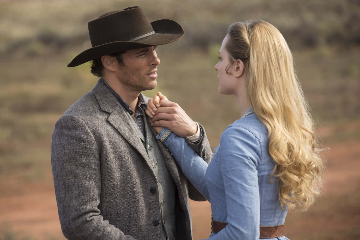James Marsden 桌布 壁紙 — 一個牛仔和一個穿著時代服裝的女人在陽光明媚的沙漠景觀中分享親密時刻。