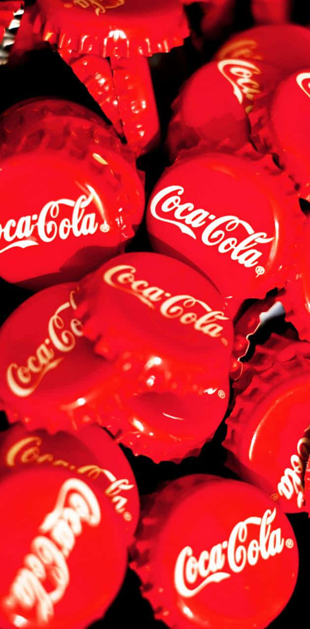Coca Cola Logo 桌布 壁紙 — 一個特寫，顯示光澤的紅色可口可樂瓶蓋堆疊在深色背景上。