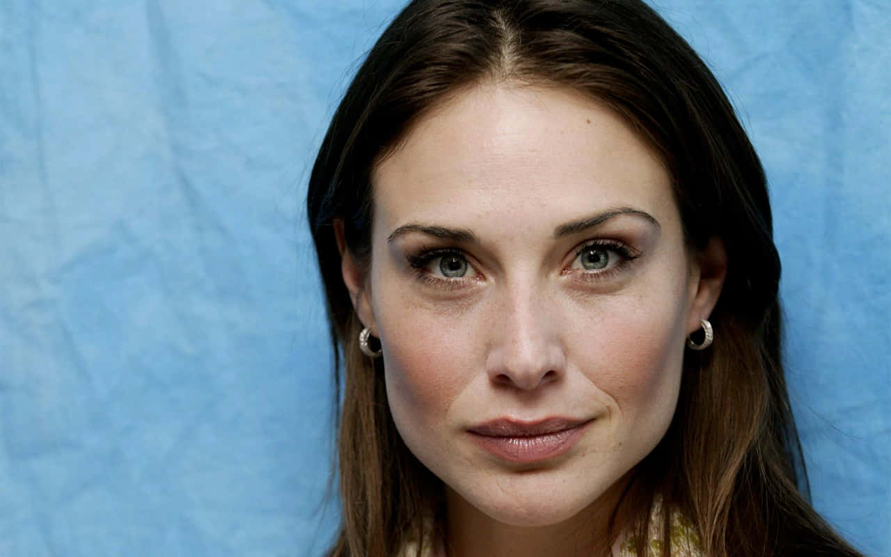 Claire Forlani 桌布 壁紙 — 一個特寫肖像，一位擁有綠色眼睛和深色頭髮的女性，背景是帶有紋理的藍色。