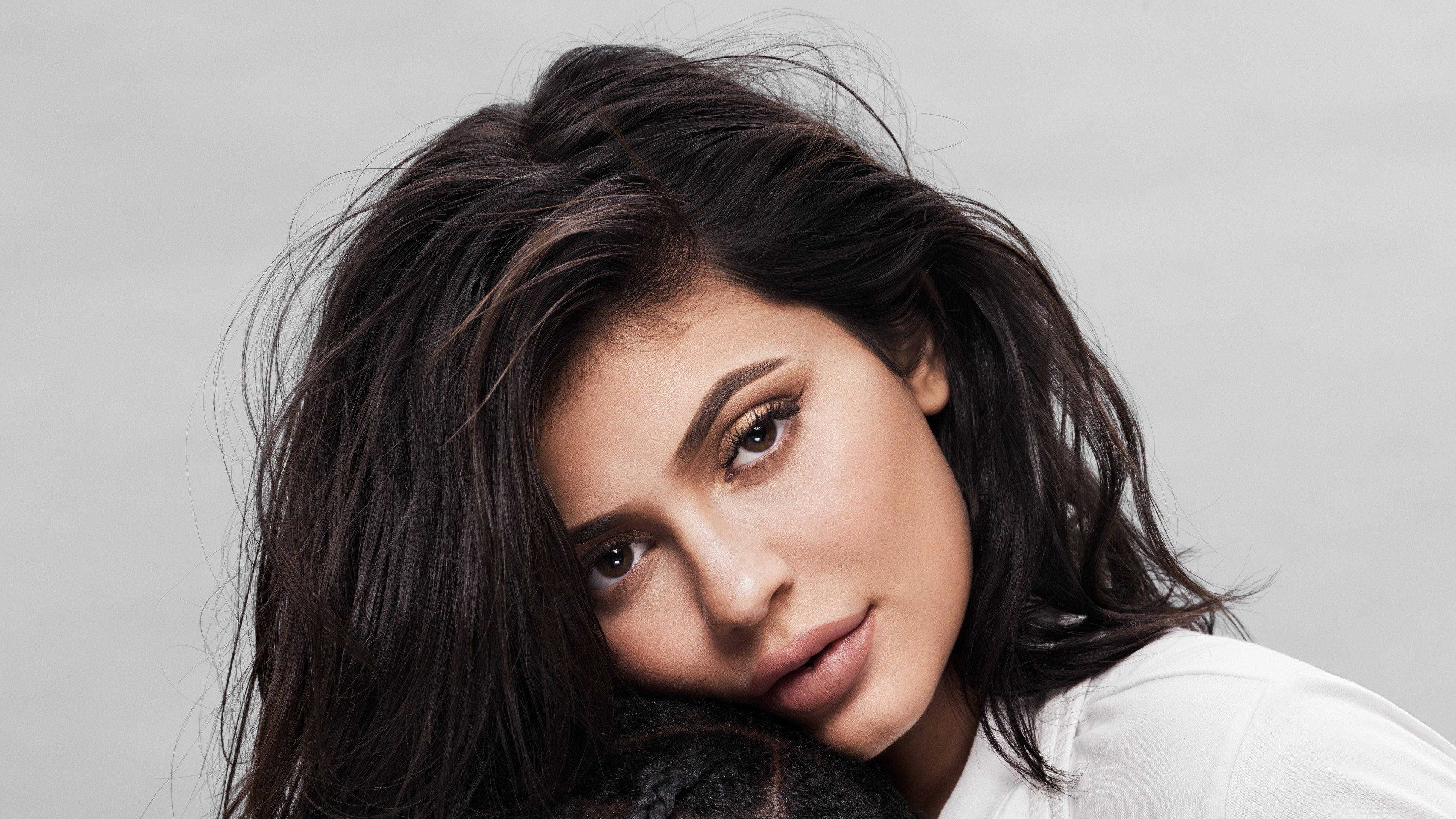 Kylie 桌布 壁紙 — 一個特寫肖像，一位深色凌亂頭髮、眼神強烈的女性，背景是純灰色。