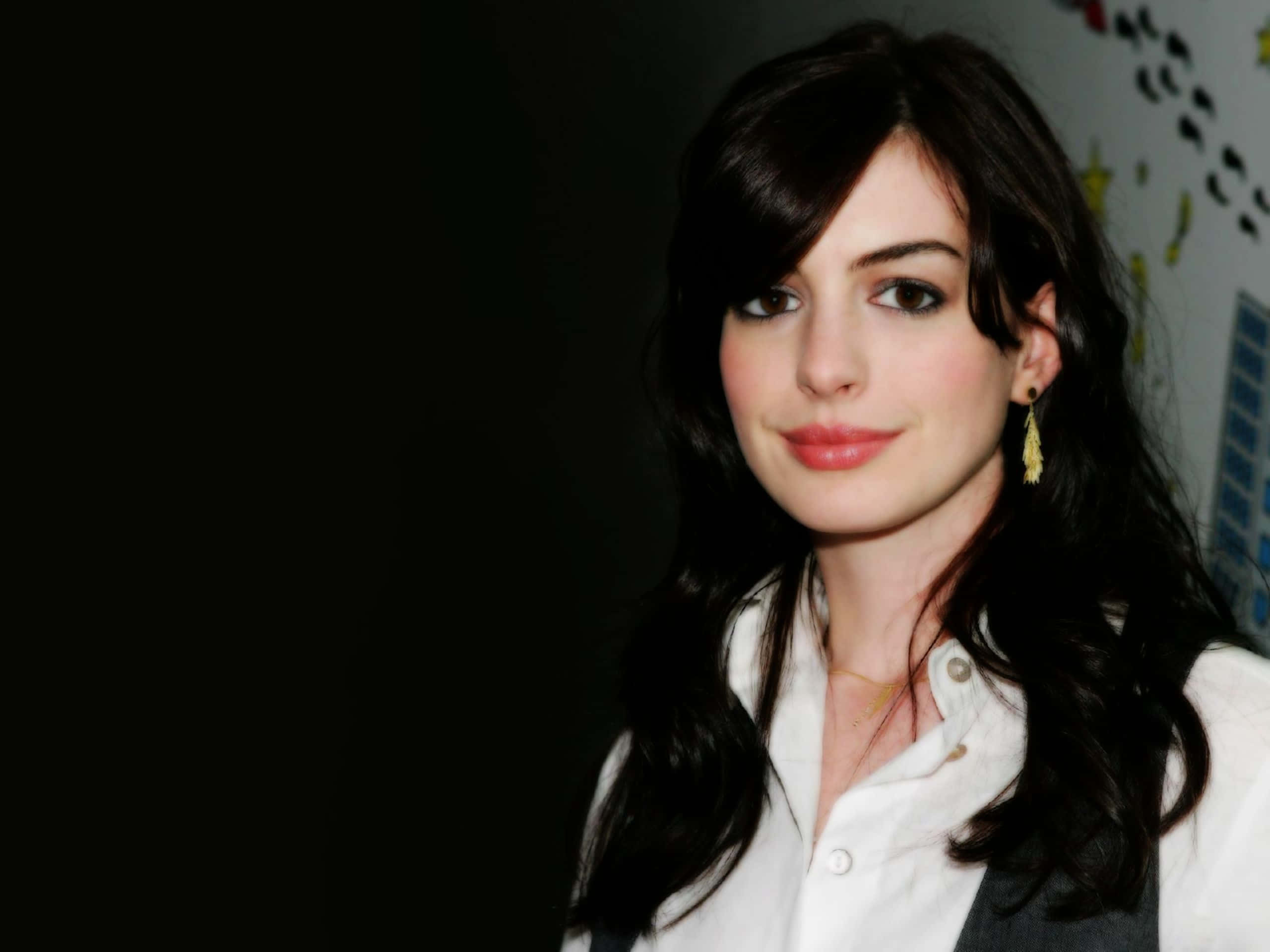 Anne Hathaway 桌布 壁紙 — 一個特寫肖像，一位深色波浪髮、身穿白襯衫的女性，背景為深色。