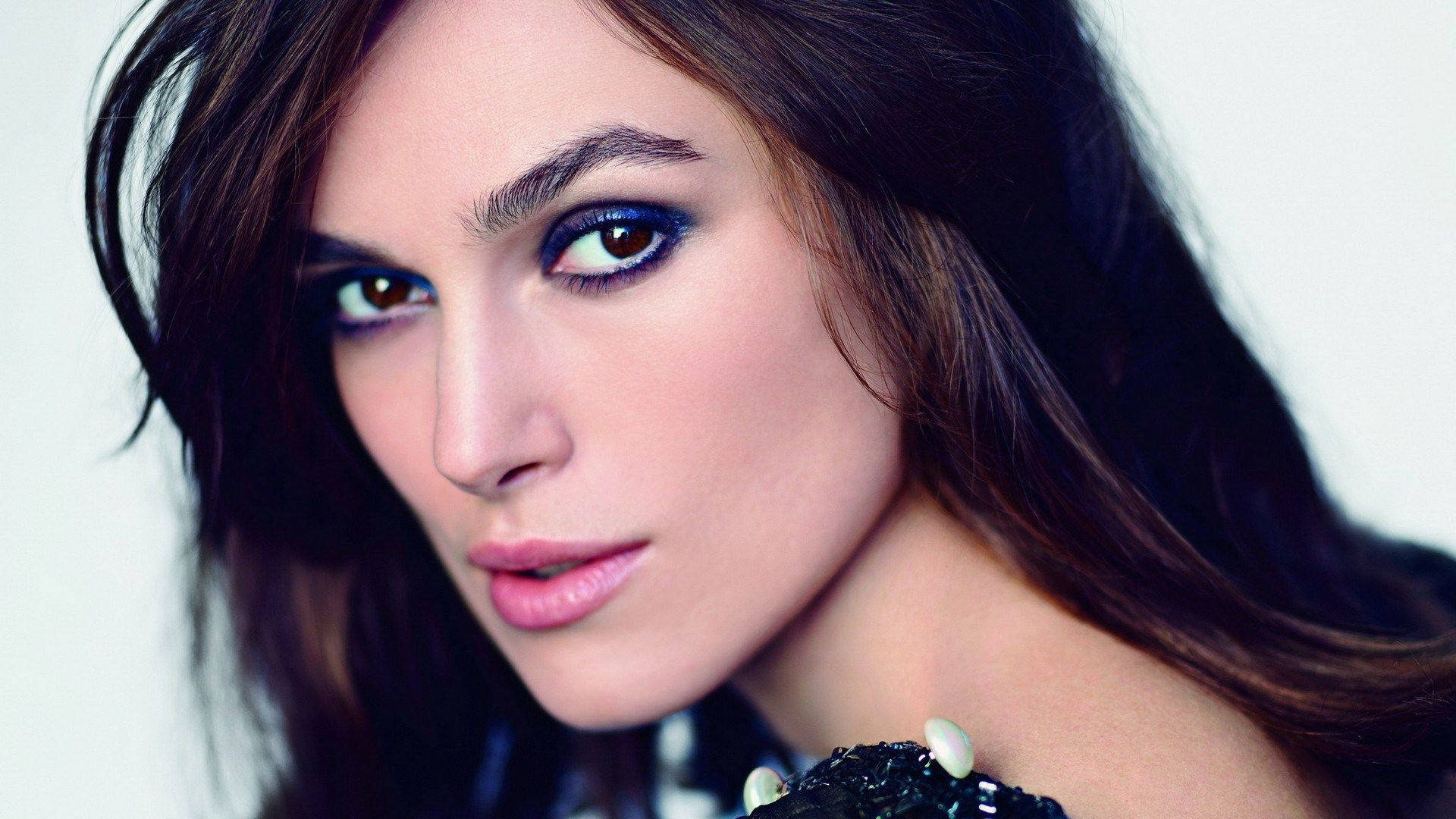 Keira Knightley 桌布 壁紙 — 一個特寫肖像，一位深色頭髮、煙燻眼妝的女性，在純白背景下凝視鏡頭。