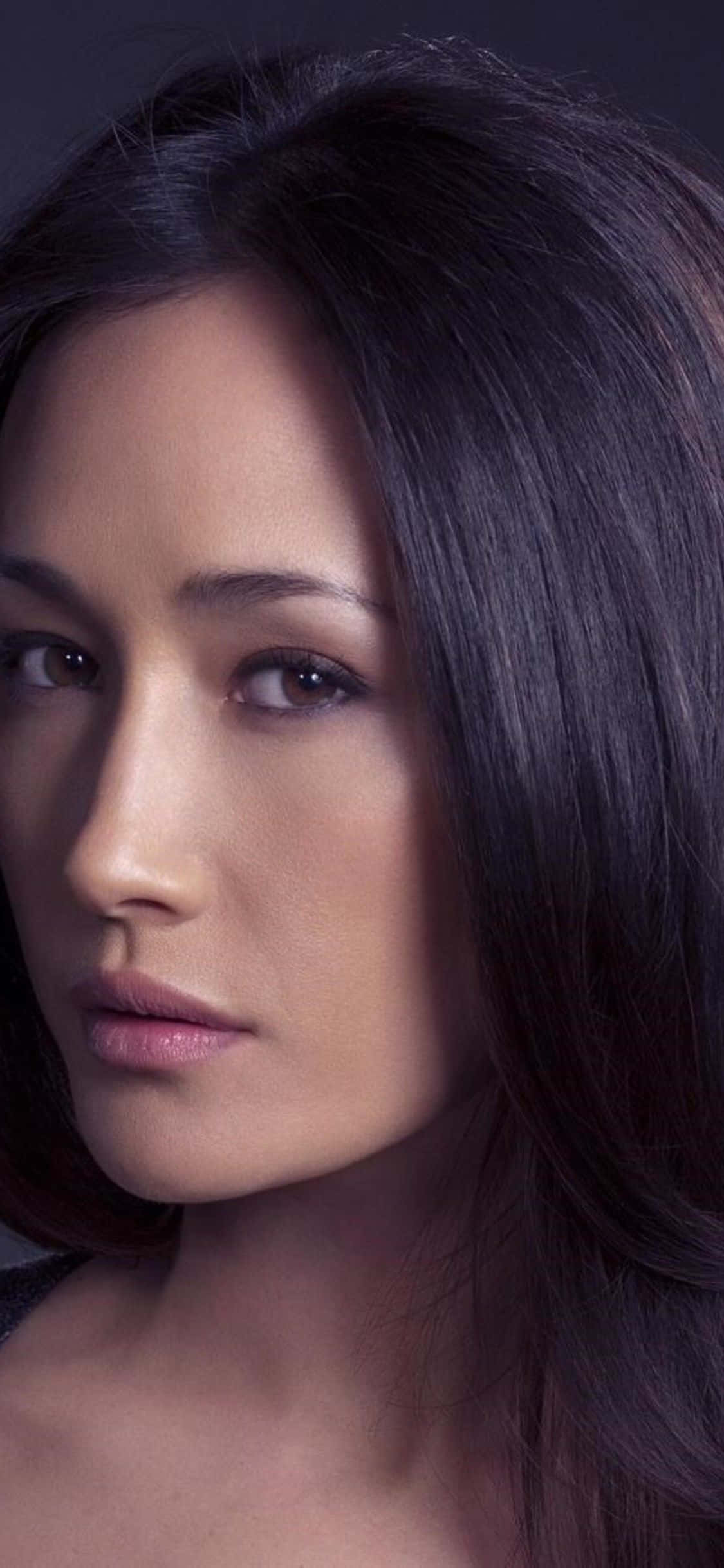 maggie q 桌布 壁紙 — 一個特寫肖像，一位深色頭髮、眼神強烈的女性，背景為柔和的灰色。