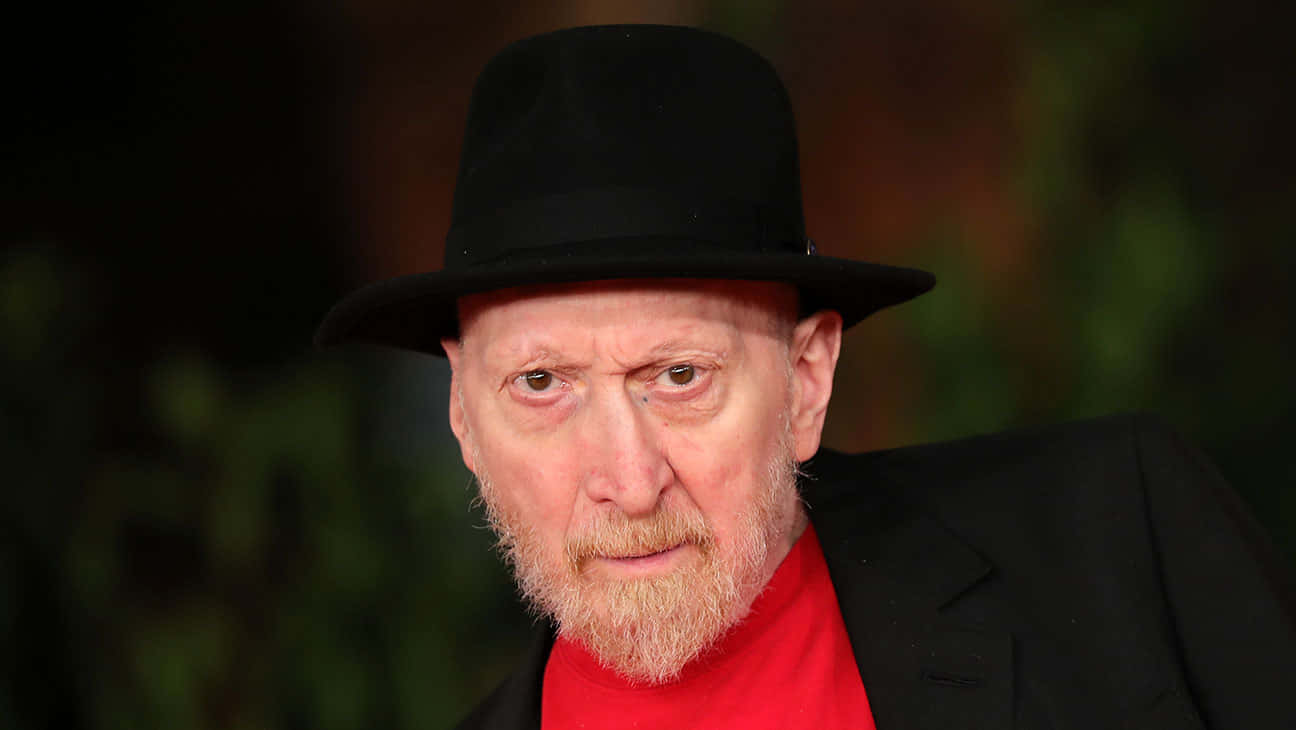 Frank Miller 桌布 壁紙 — 一個特寫肖像，一個留著白鬍子的男人戴著黑色軟呢帽和紅色襯衫，背景是模糊的綠色。