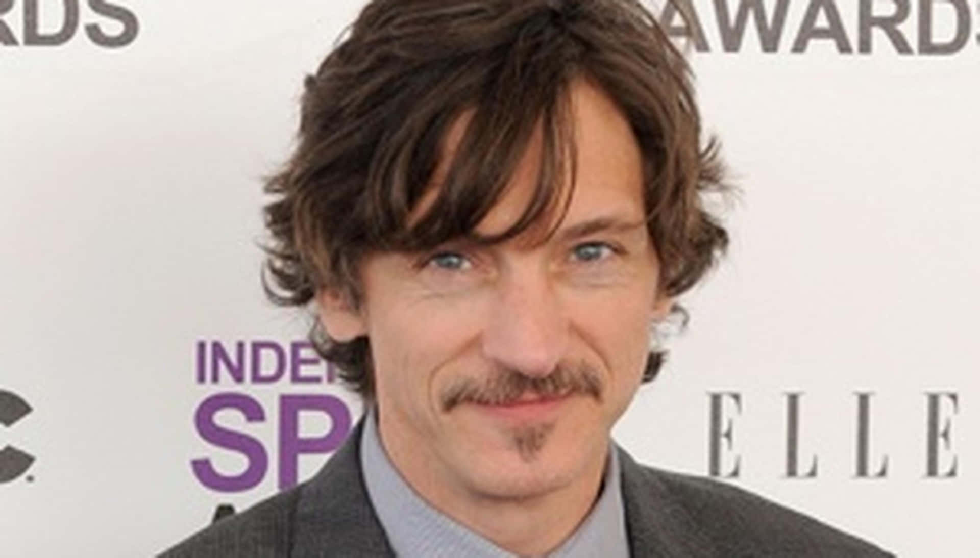 John Hawkes 桌布 壁紙 — 一個特寫肖像，一名棕色頭髮、留鬍鬚的男子在白色活動背景前對著鏡頭微笑。
