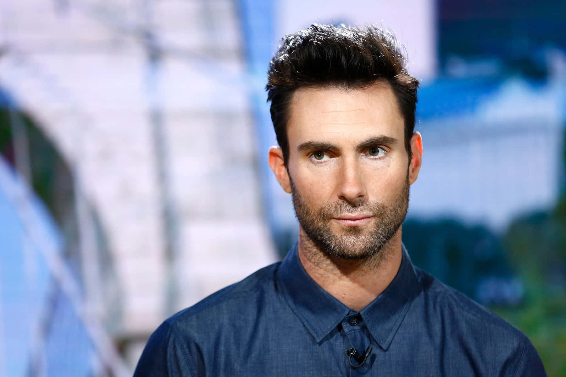 Adam Levine 桌布 壁紙 — 一個特寫肖像，一名深色頭髮和鬍鬚的男子穿著深藍色襯衫，背景模糊。