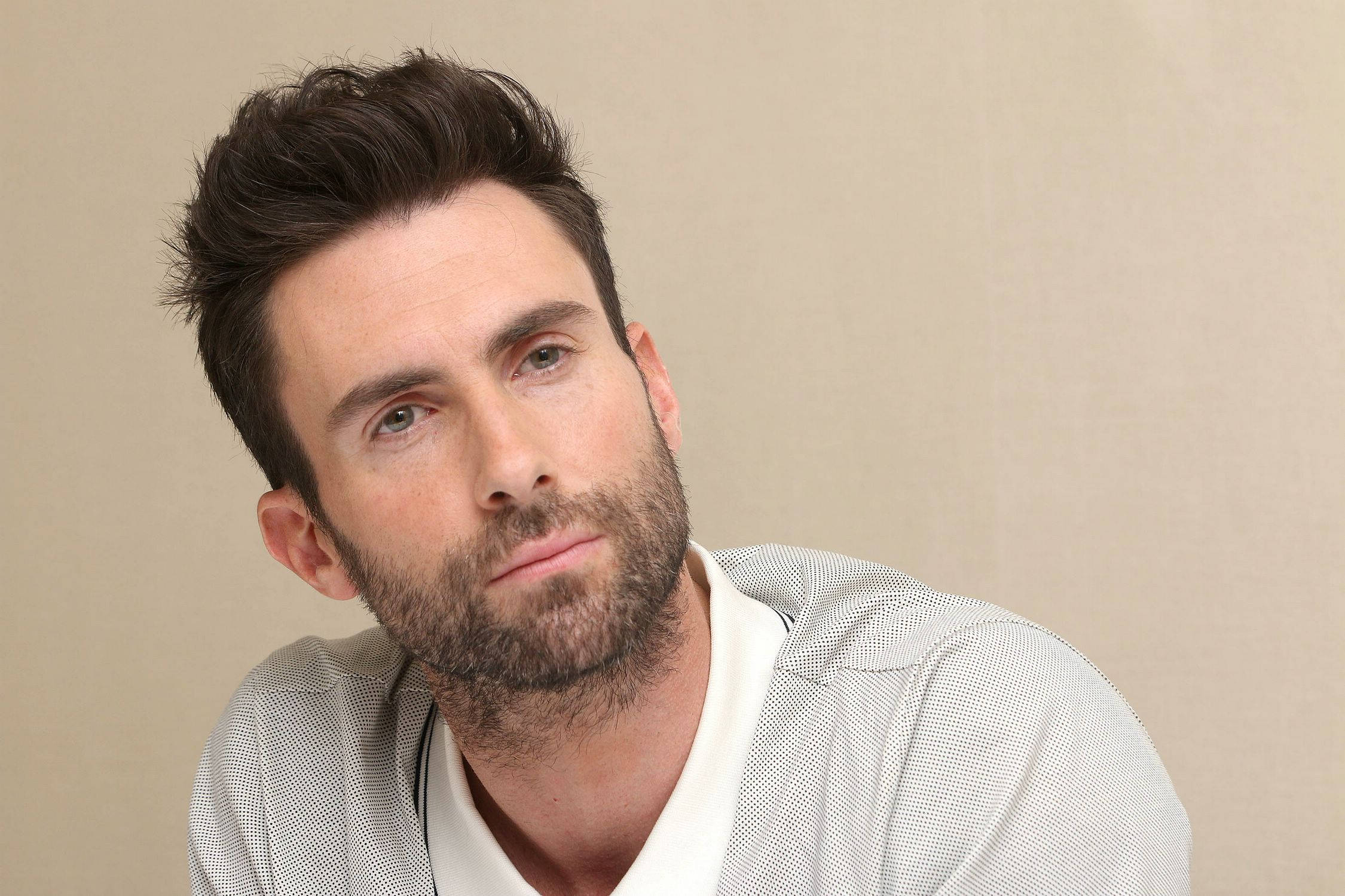 Adam Levine 桌布 壁紙 — 一個特寫肖像，一名深色頭髮和鬍鬚的男子穿著圖案襯衫，背景為米色。