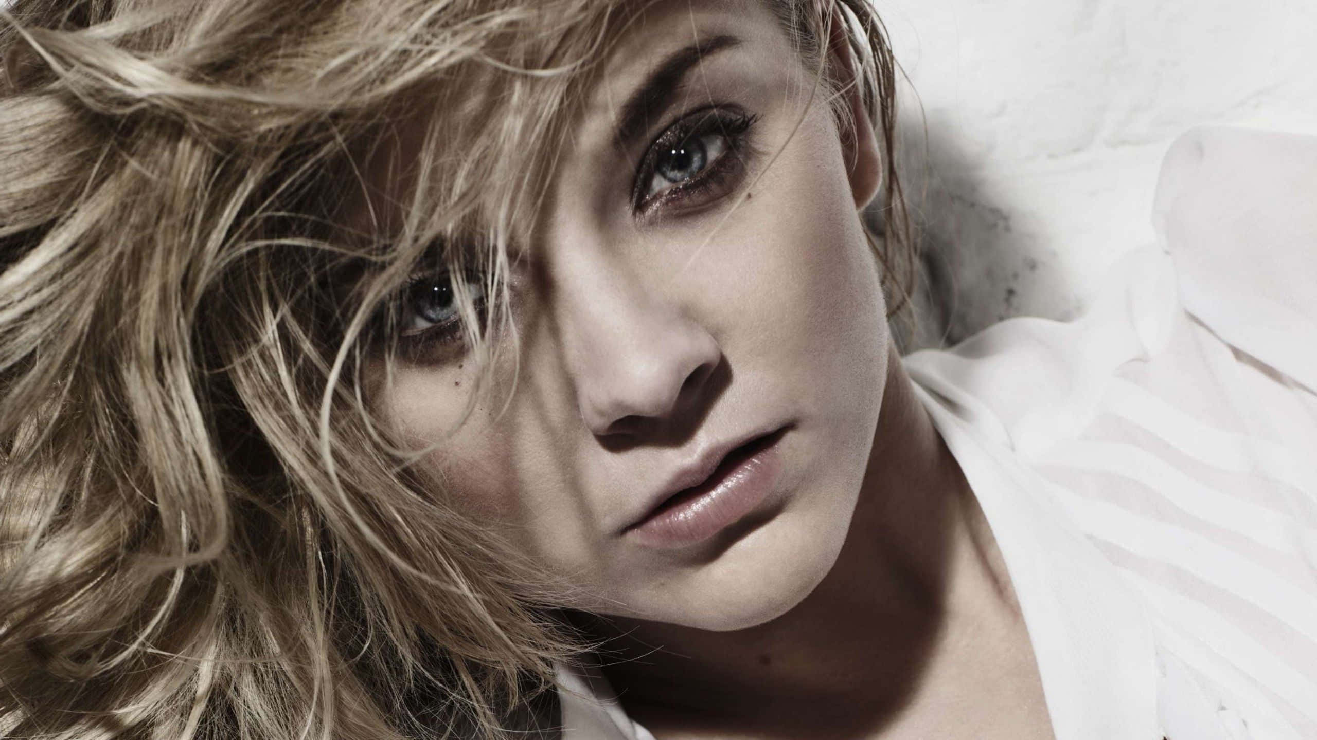 natalie dormer 桌布 壁紙 — 一個特寫鏡頭，一位擁有凌亂金髮和深邃藍眼睛的女性躺著直視相機。