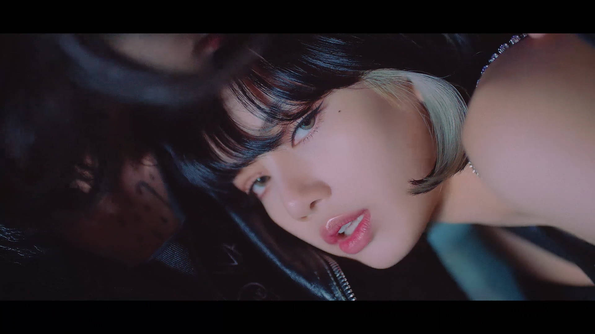 BLACKPINK 桌布 壁紙 — 一個特寫鏡頭，一位深色頭髮帶有銀色挑染的女性，在憂鬱的藍色燈光下以銳利的眼神向上看。