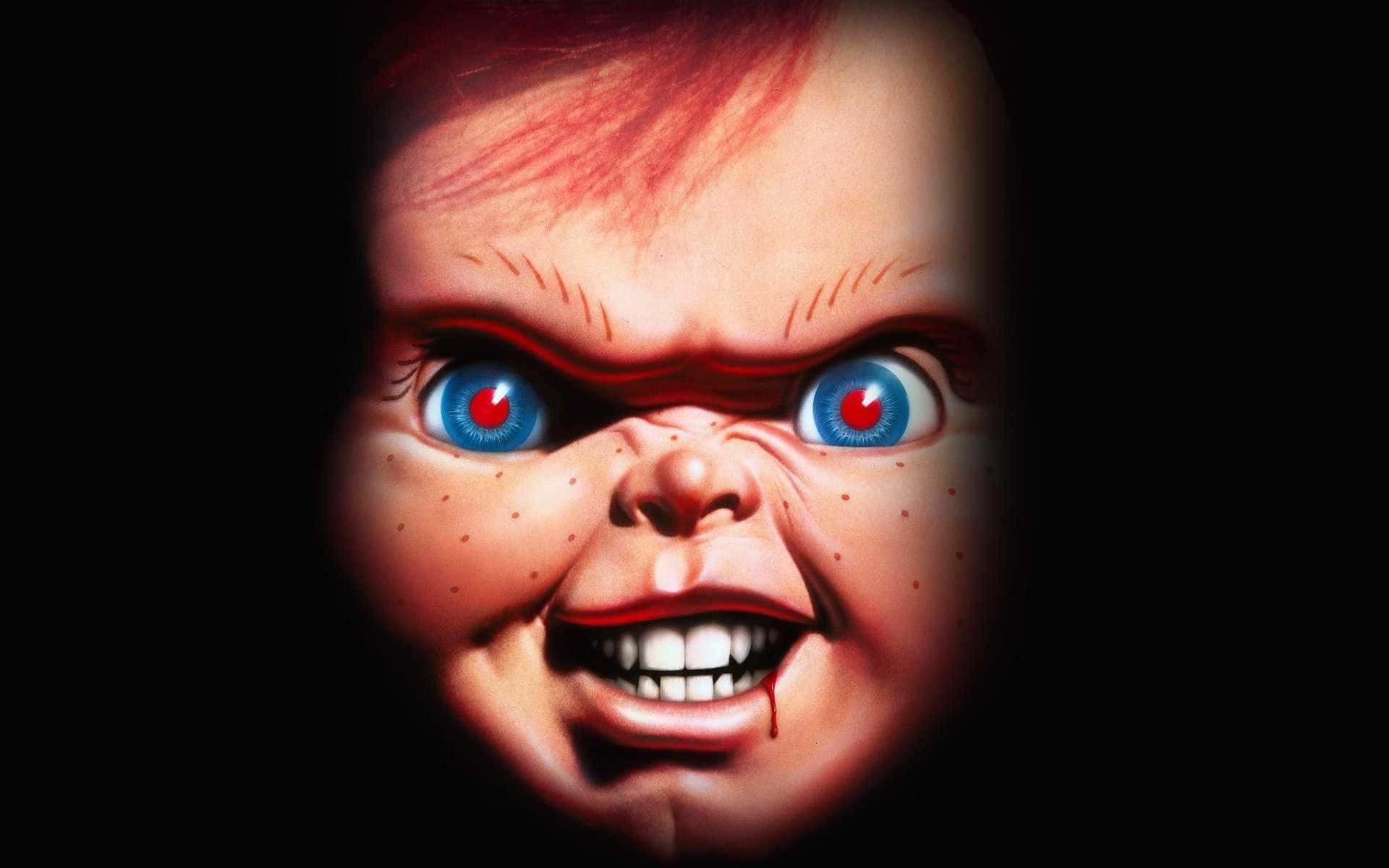 Chucky Doll 桌布 壁紙 — 一個特寫鏡頭，一個帶有藍色大眼睛、紅色瞳孔和血淋淋笑容的恐怖娃娃，背景為黑色。