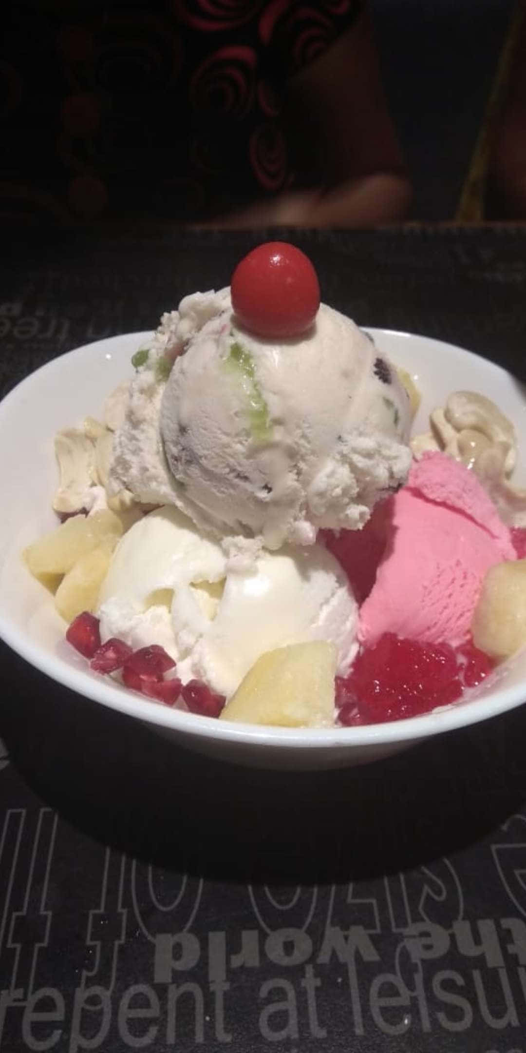 Pixel 3 Desserts 桌布 壁紙 — 一個特寫鏡頭，展示一個白色碗中盛載的奶油冰淇淋聖代，上面放著一顆櫻桃，周圍環繞著水果。