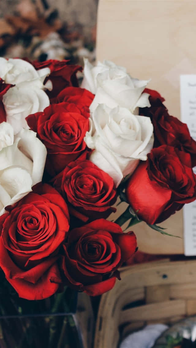 Rose Aesthetic 桌布 壁紙 — 一個特寫鏡頭，展示一束茂盛的花束，深紅色和純白色的玫瑰插在透明花瓶裡，背景是溫暖的木質背景。