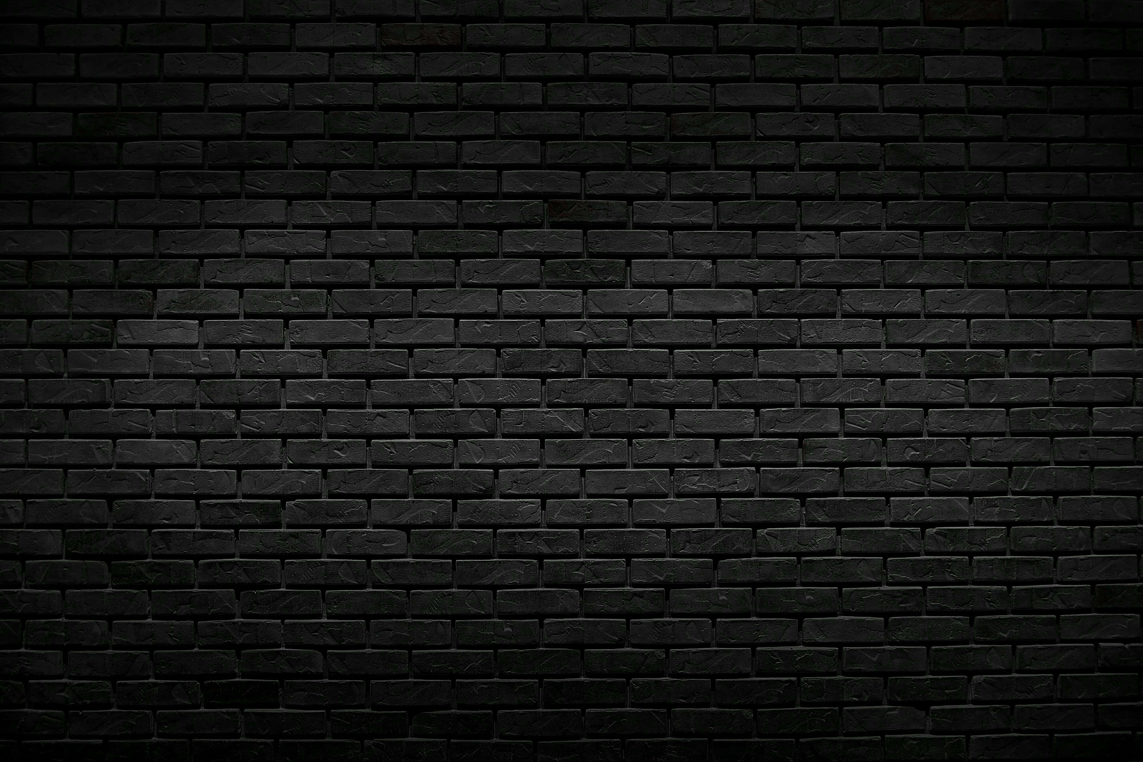 Brick 桌布 壁紙 — 一個特寫鏡頭，展示一面深色紋理磚牆，表面帶有微妙的燈光變化。