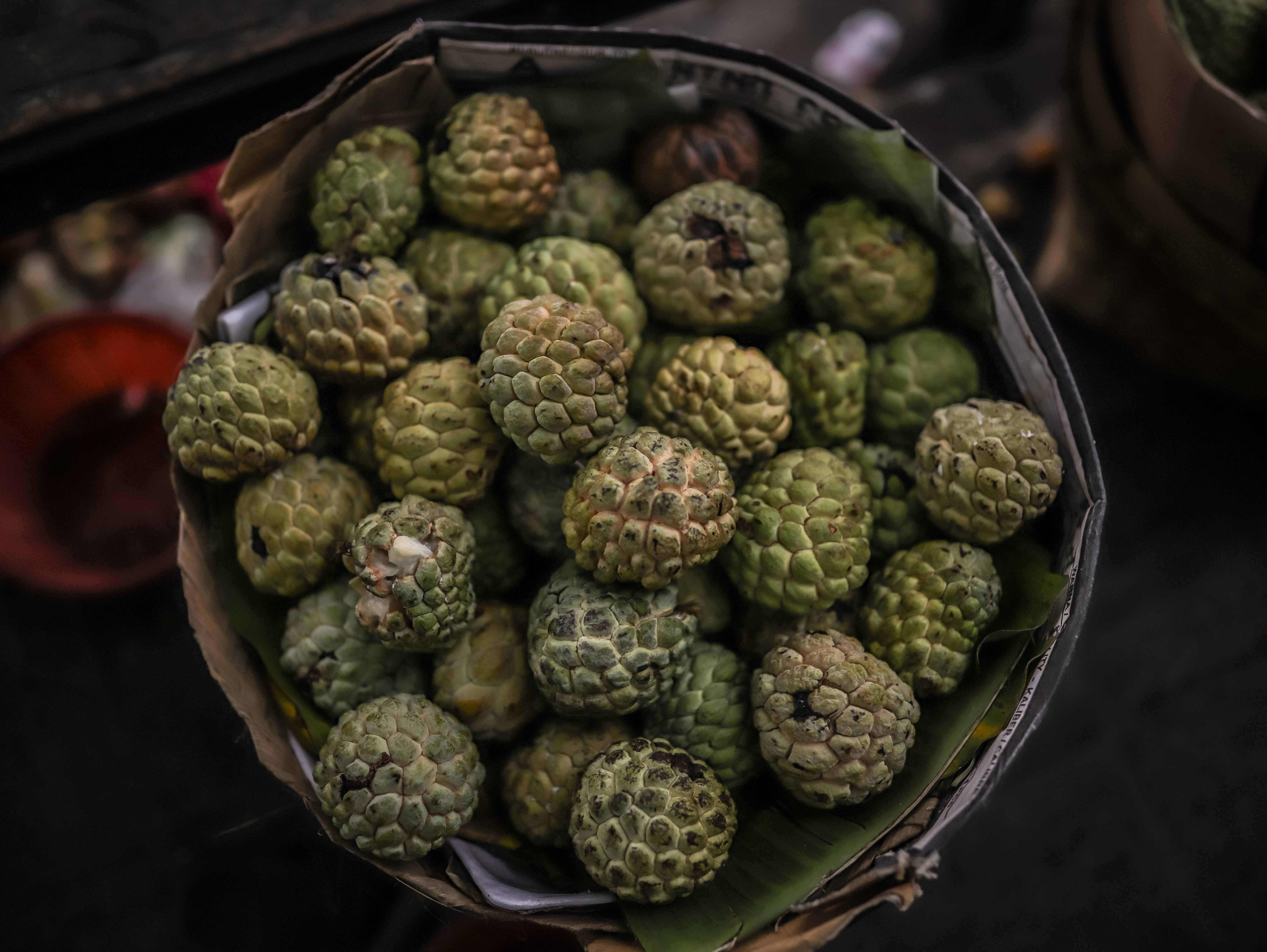 Fruit 桌布 壁紙 — 一個特寫鏡頭，展示編織籃子裡襯著香蕉葉，裝滿了帶刺的綠色釋迦果。