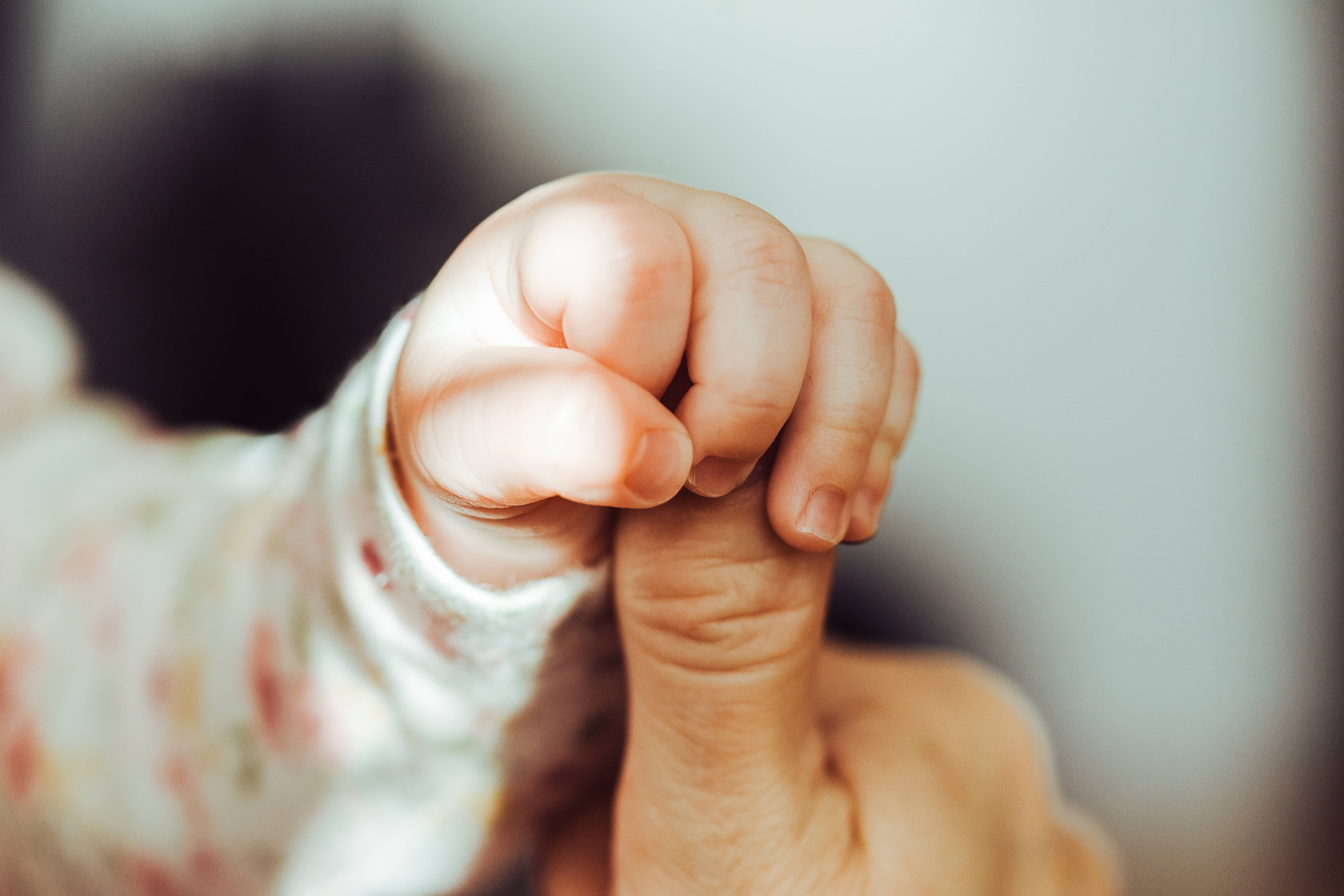 Baby HD 桌布 壁紙 — 一個特寫鏡頭，捕捉孩子的小手溫柔地緊握著成人的手指，充滿親密感。