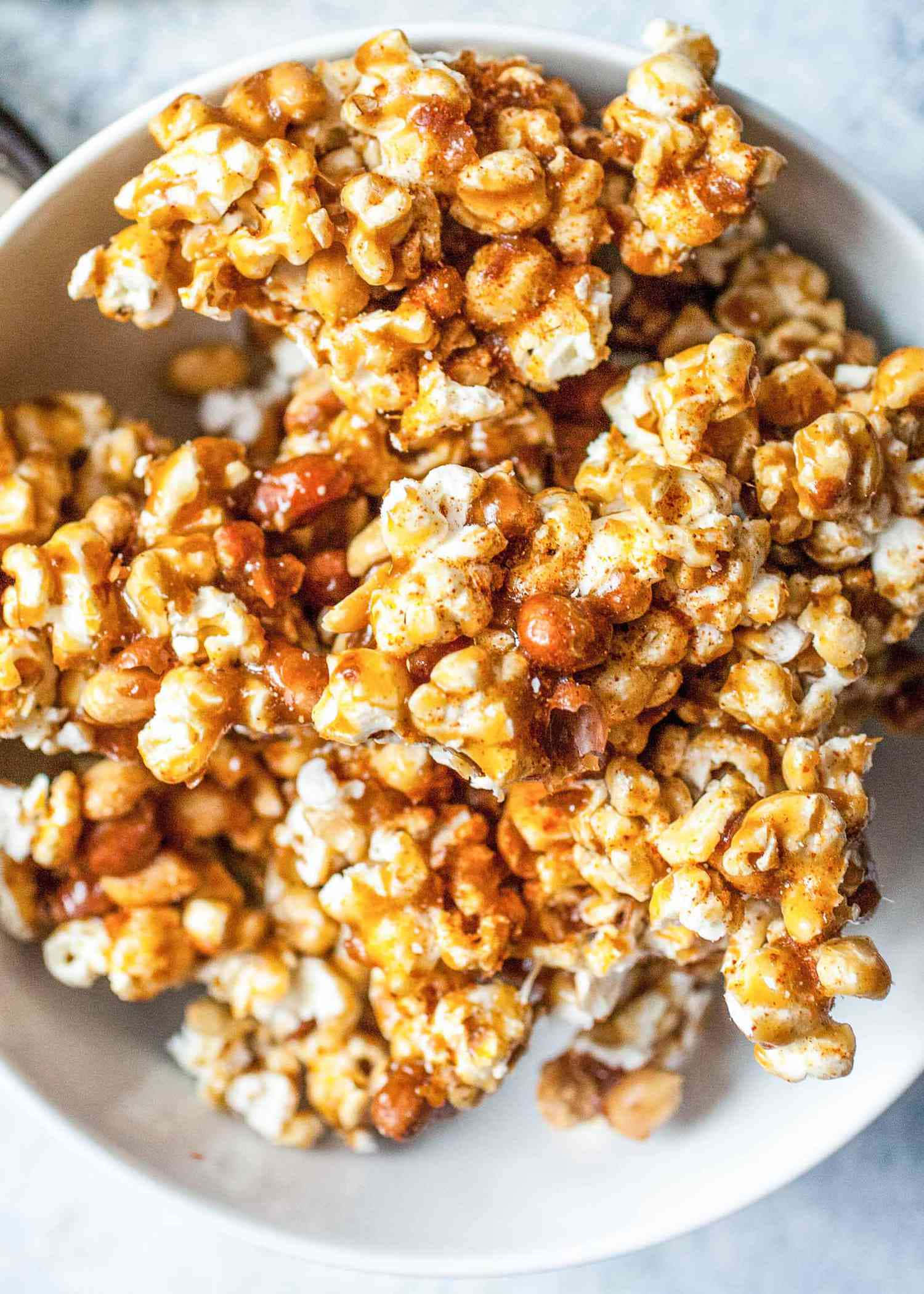 Popcorn 桌布 壁紙 — 一個特寫鏡頭，焦糖包裹的爆米花混合花生從白色碗中溢出。