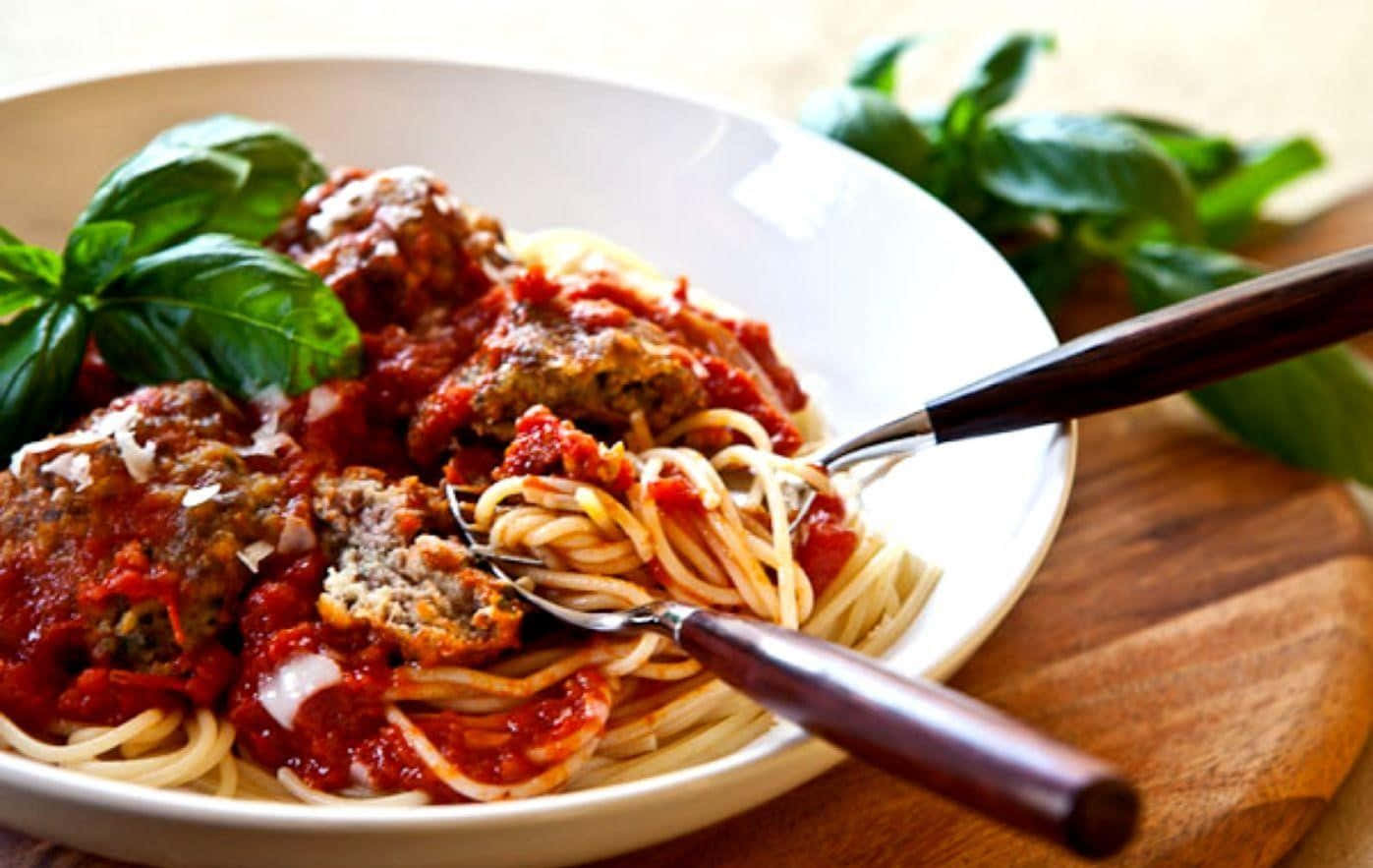 Pasta 桌布 壁紙 — 一個特寫鏡頭，白色碗中的義大利麵肉丸配上濃郁番茄醬，並以新鮮羅勒葉點綴。
