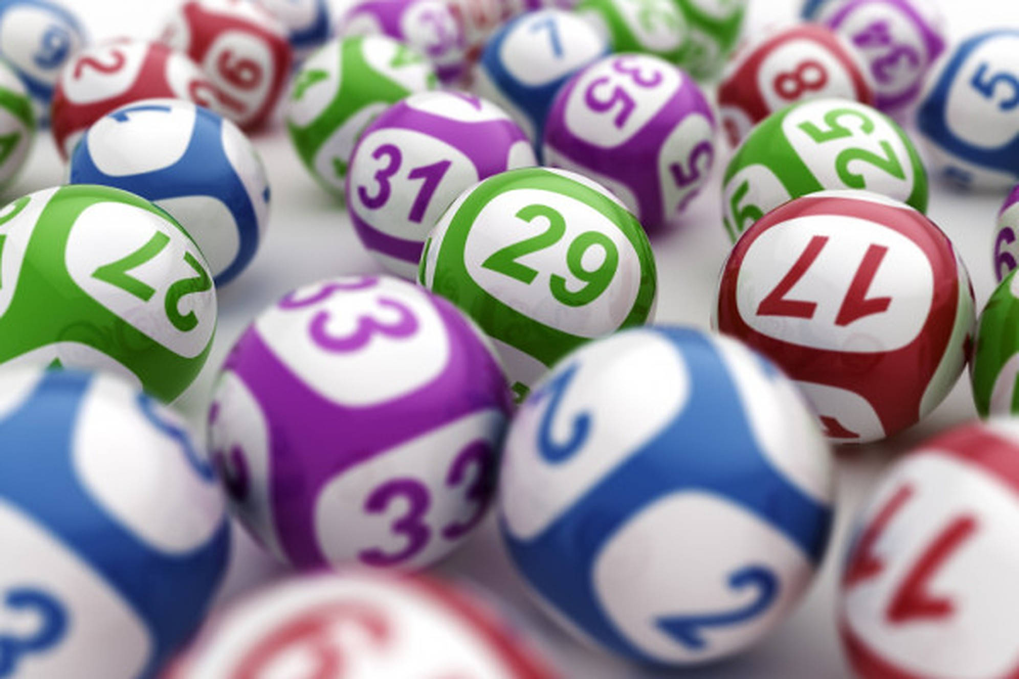 Lottery 桌布 壁紙 — 一個特寫鏡頭，顯示帶有29、31和17等數字的彩色樂透球散落在白色表面上。