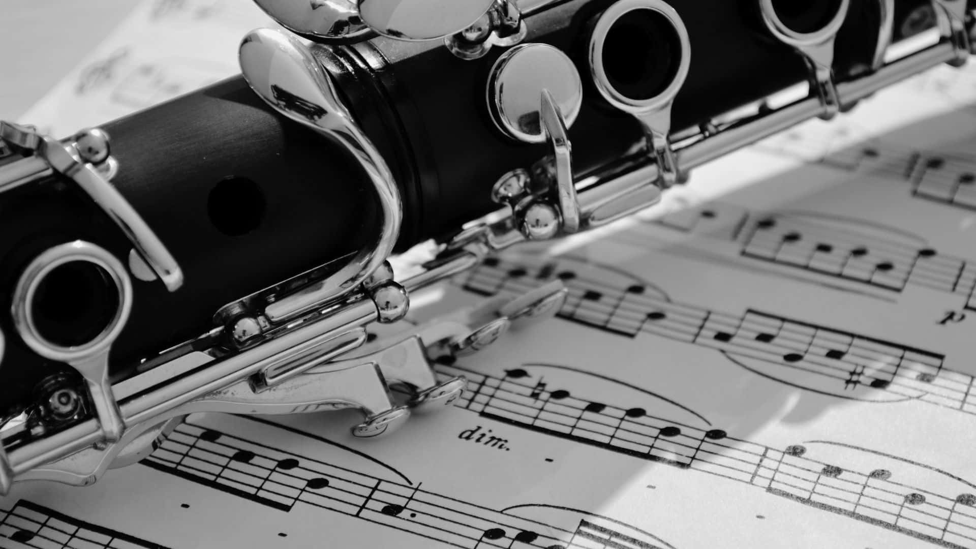 Black And White Music 桌布 壁紙 — 一個特寫黑白鏡頭，單簧管放在樂譜上，樂譜上有可見的音符和力度記號。
