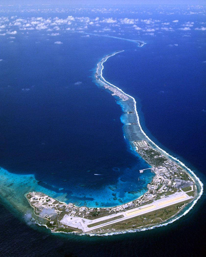 Marshall Island 桌布 壁紙 — 一個狹長環礁島嶼的鳥瞰圖，設有機場跑道、碧綠潟湖和深藍色海洋。