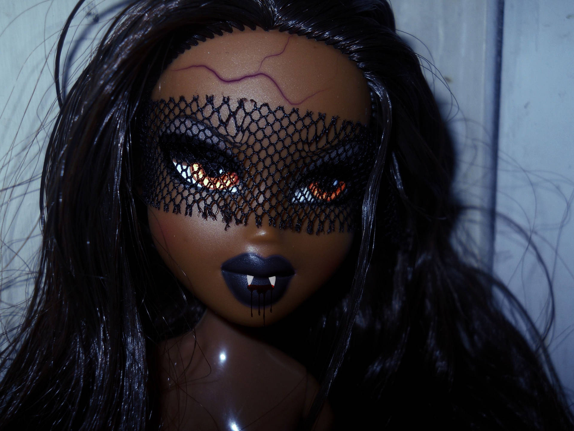 Bratz 桌布 壁紙 — 一個玩偶的特寫，戴著黑色蕾絲眼罩，琥珀色發光的眼睛和滴著黑色液體的尖牙，背景是柔和的牆壁。