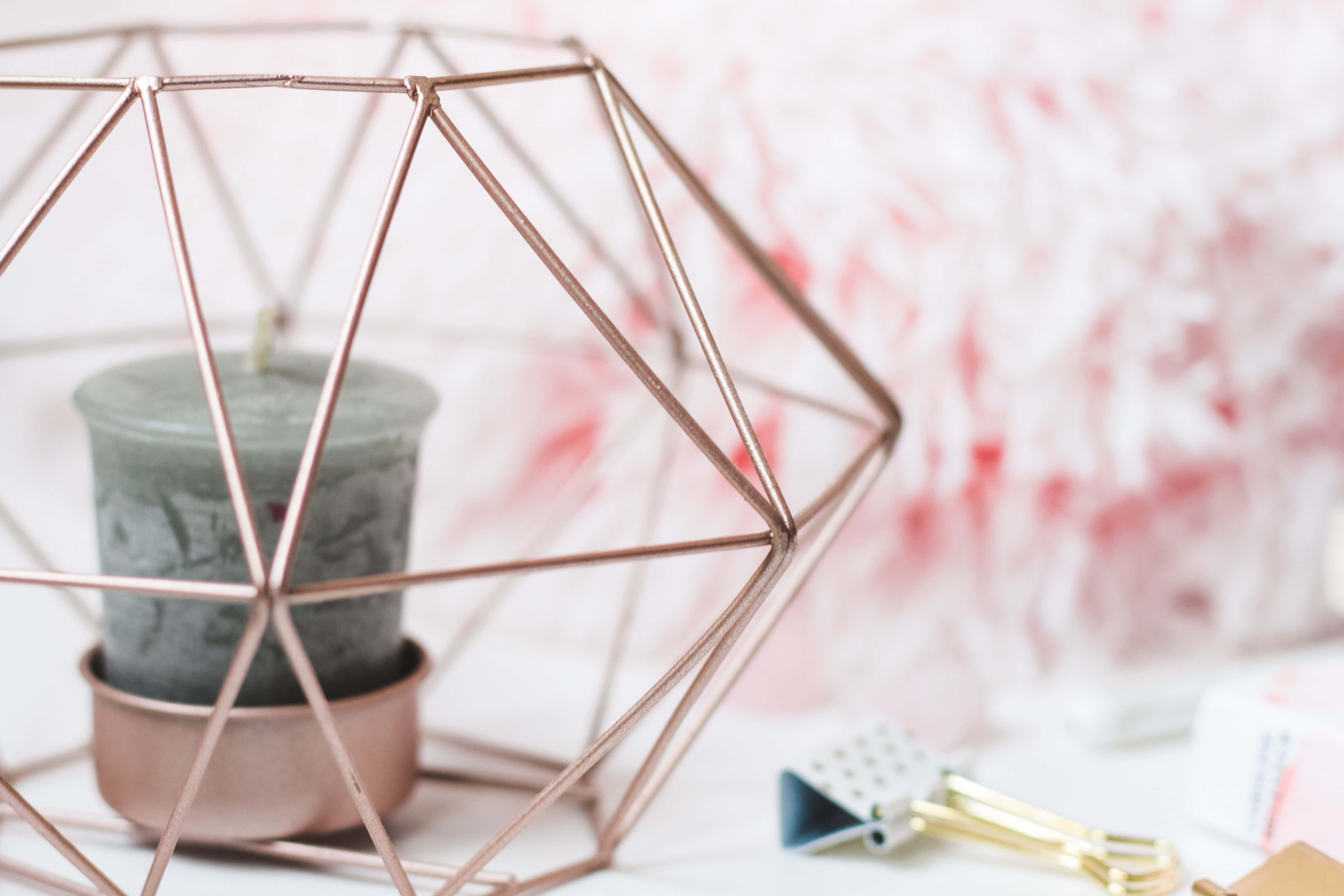 Rose Gold Desktop 桌布 壁紙 — 一個玫瑰金幾何燭台，在柔和粉紅花卉背景上托著一支灰色蠟燭。