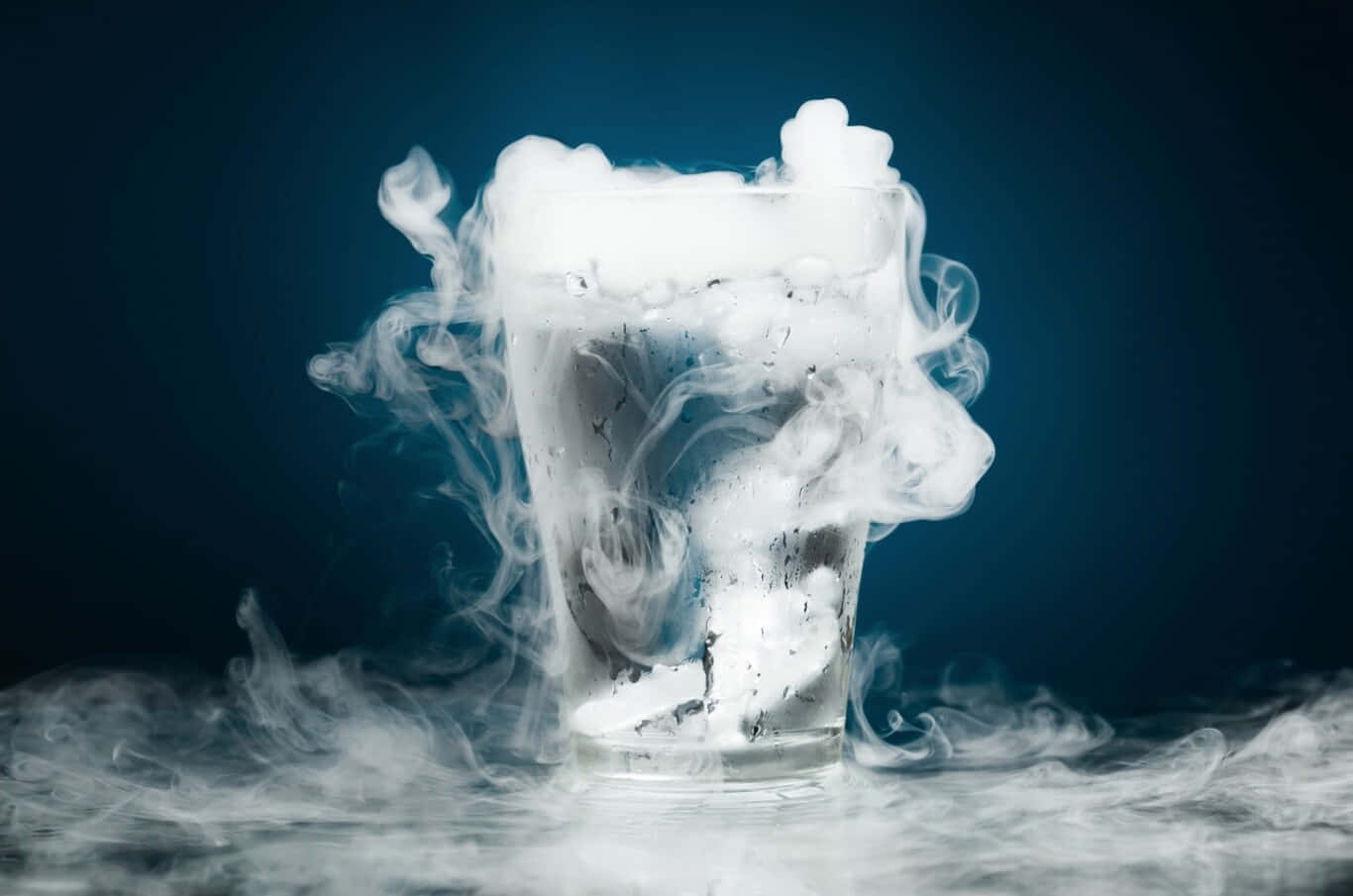 Gas 桌布 壁紙 — 一個玻璃杯裝滿旋轉的白色蒸氣，在深藍色背景下營造出神秘而酷炫的氛圍。