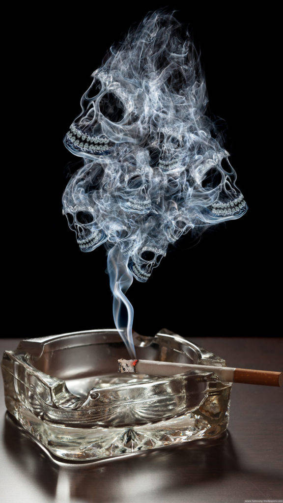 頭骨 桌布 壁紙 — 一個玻璃煙灰缸盛著一支點燃的香煙，升起的煙霧在黑色背景上形成鬼魂般的頭骨。