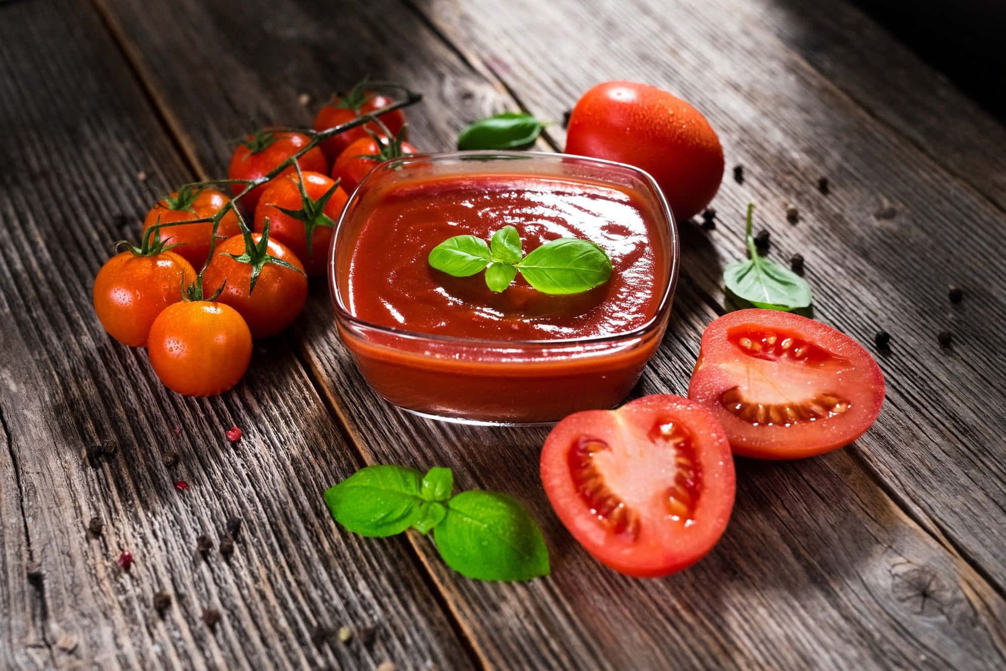 Red Sauce 桌布 壁紙 — 一個玻璃碗盛裝著濃郁的紅色番茄醬，上面點綴著羅勒葉，旁邊放著新鮮的櫻桃番茄和切片番茄，置於經風化的木質表面上。