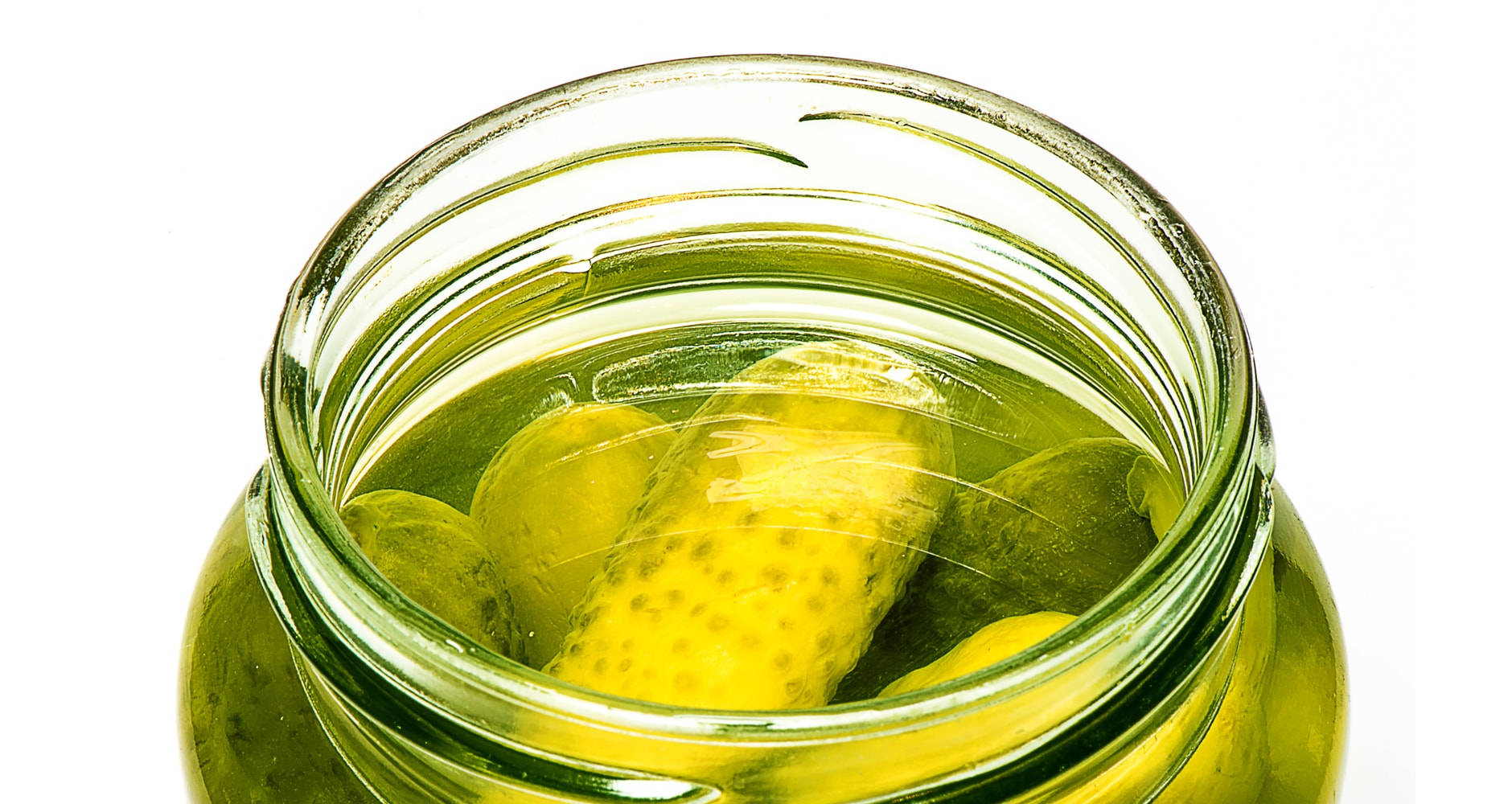 Pickle 桌布 壁紙 — 一個玻璃罐的特寫，裡面裝滿了鮮綠色的醃黃瓜，浸泡在鹽水中，背景為白色。
